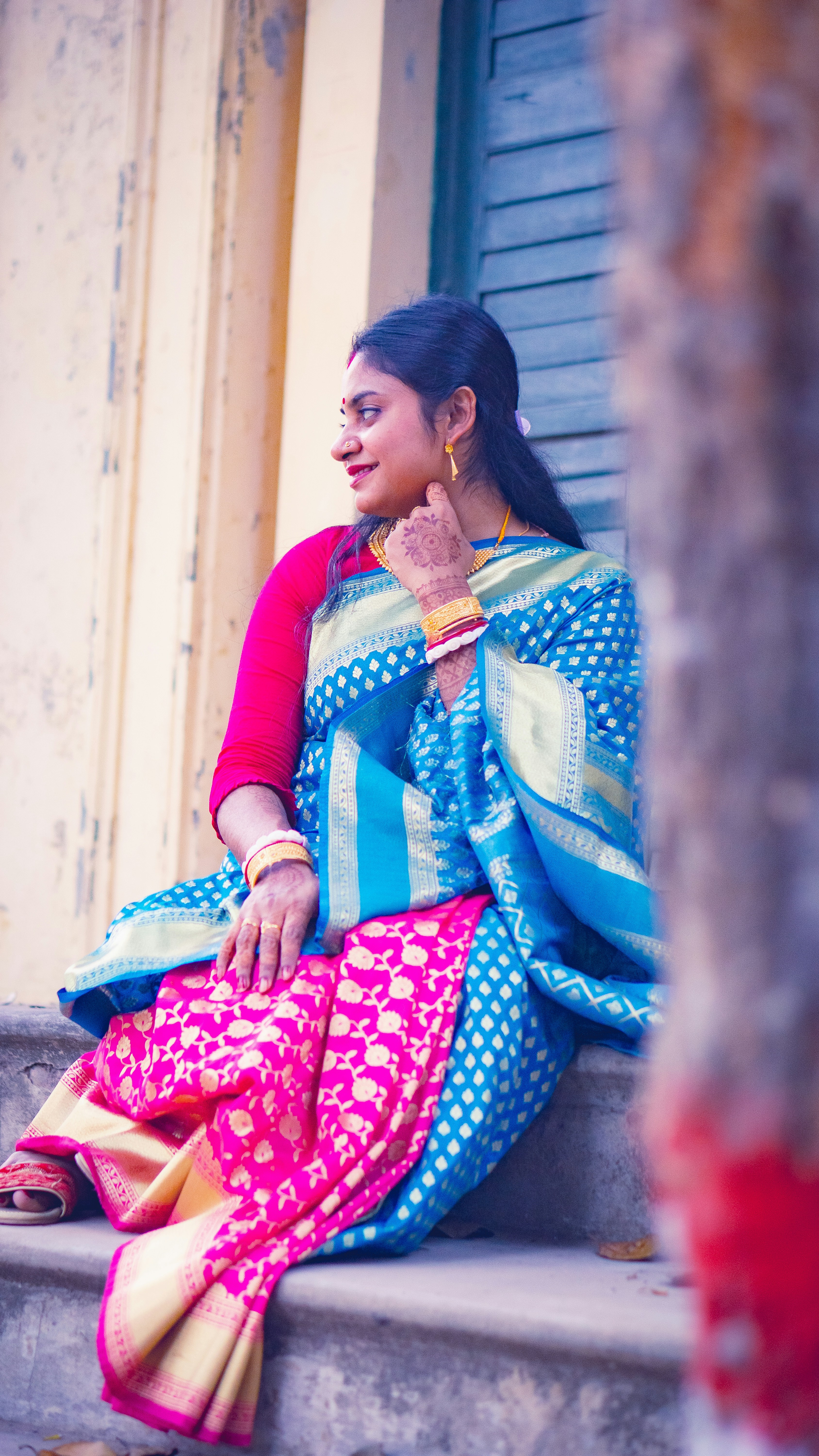 A woman in a blue and pink patterned sari sitting on stone steps