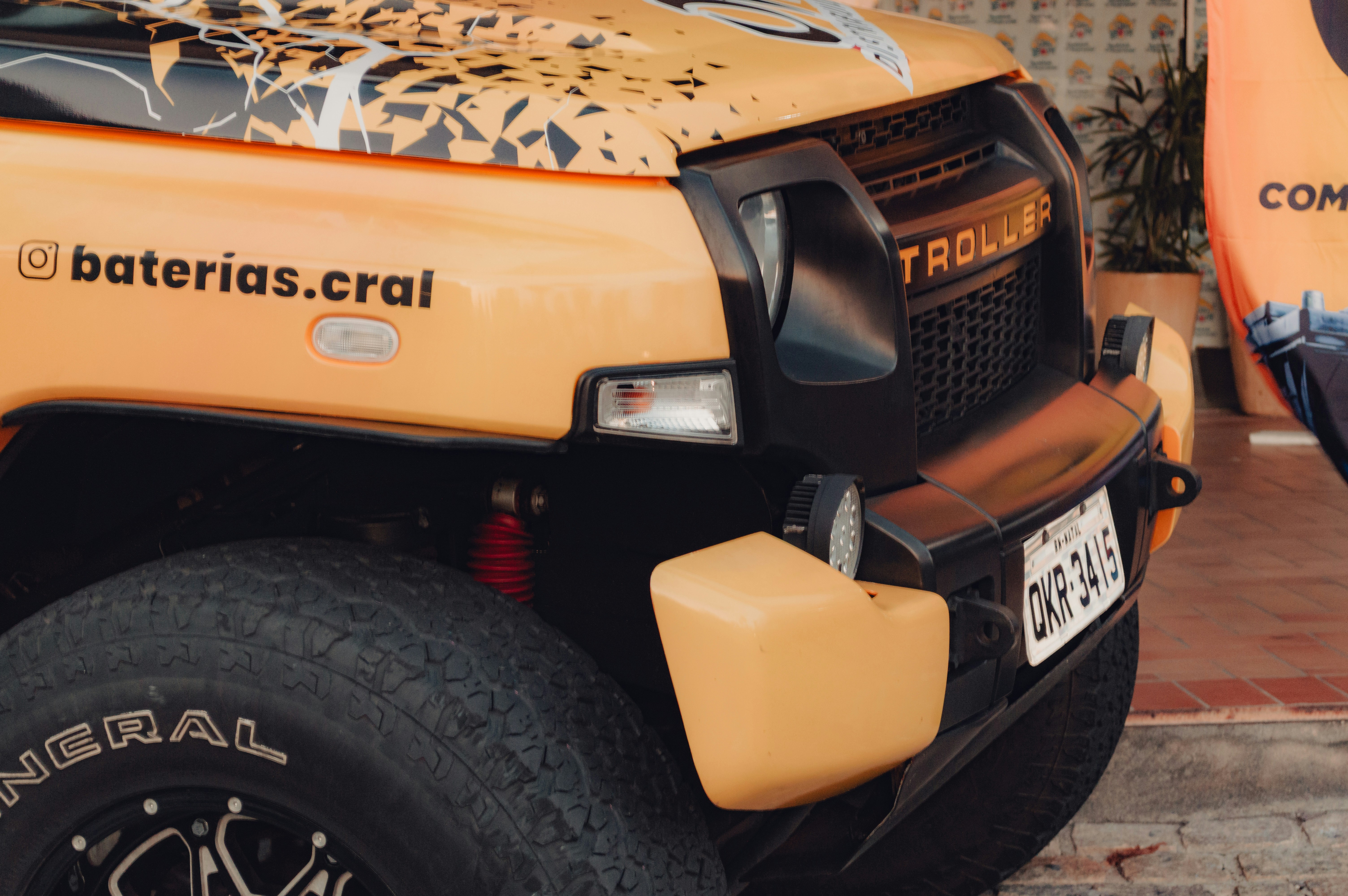 The front of a yellow Troller off-road vehicle with black trim and large tires