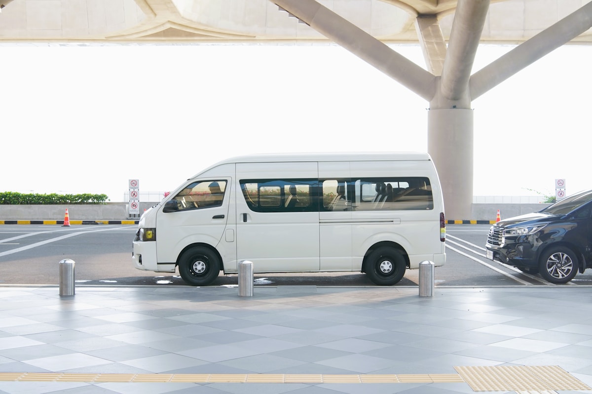 停在航廈接送區頂棚下的白色接駁廂型車