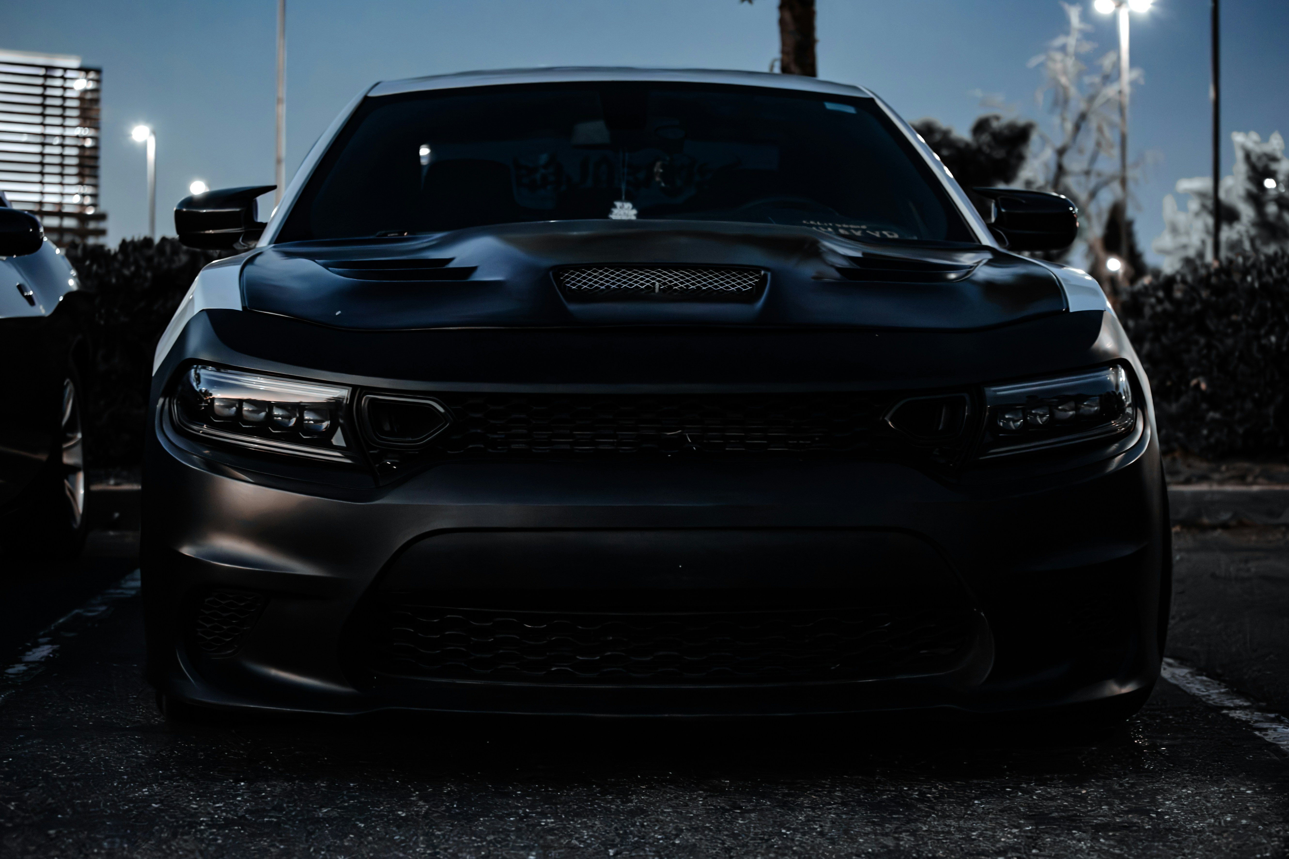 A matte black sedan parked in a lot under cool evening light