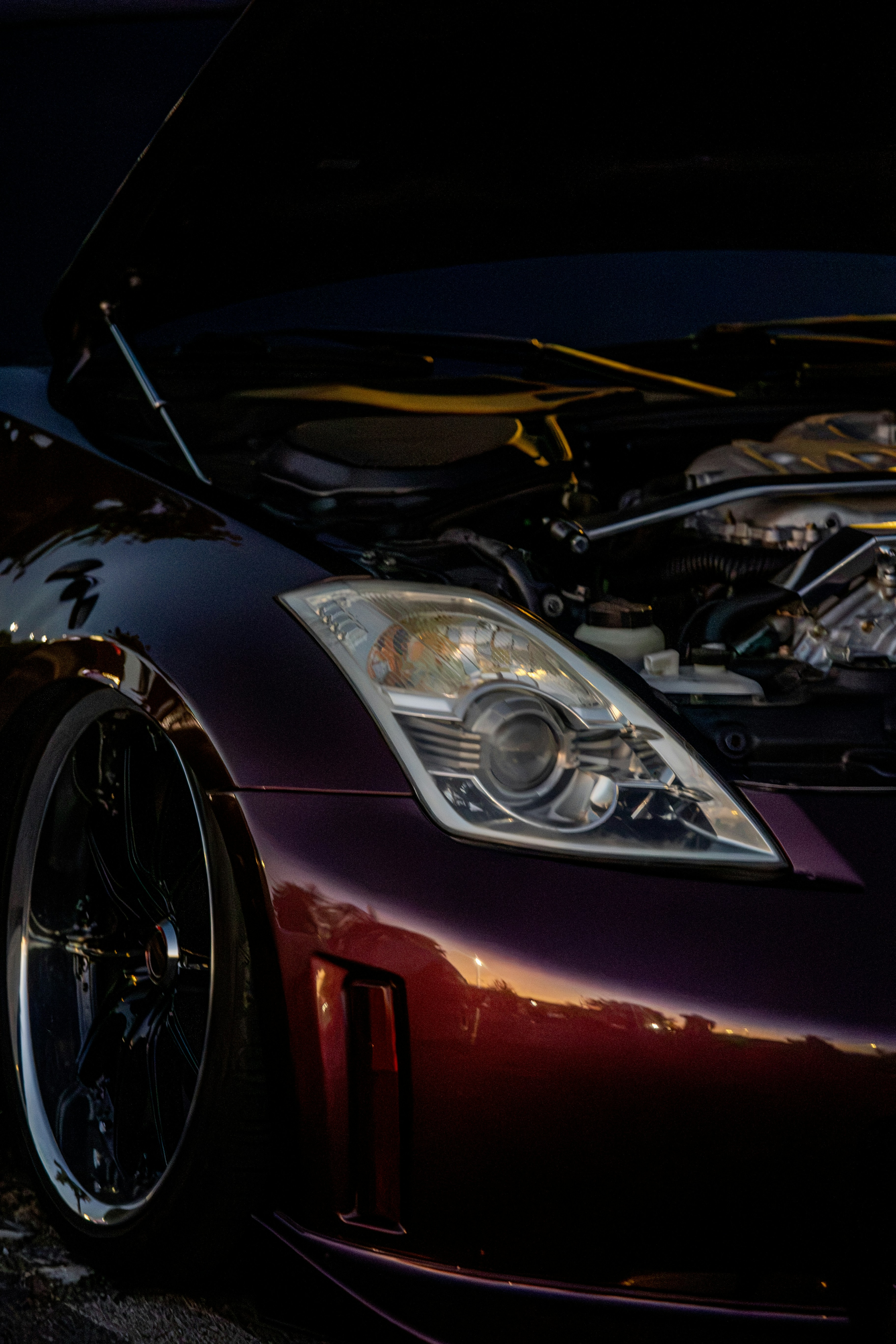A dark purple sports car with an open hood and exposed engine