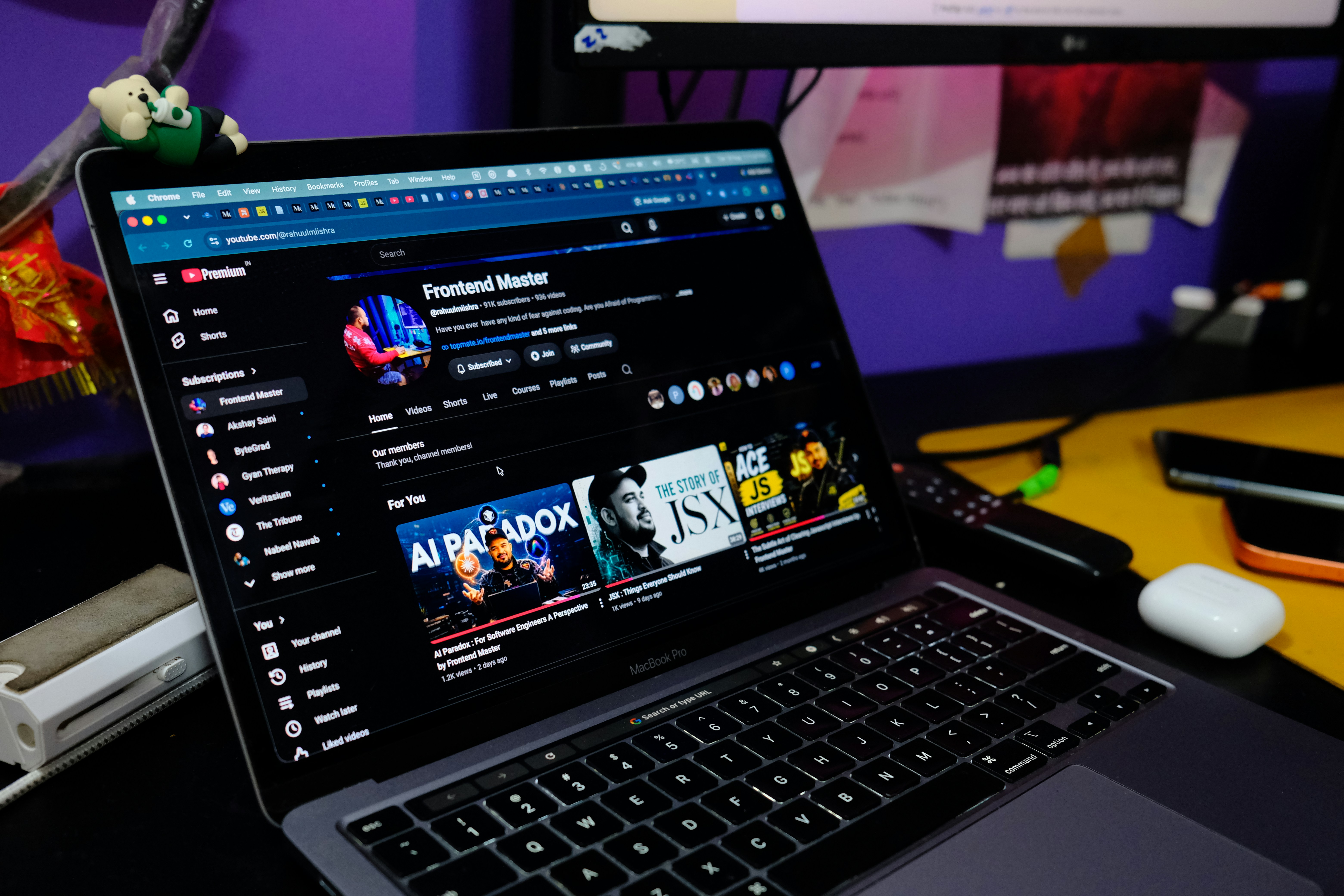 A laptop screen displaying a YouTube channel page on a dark desk