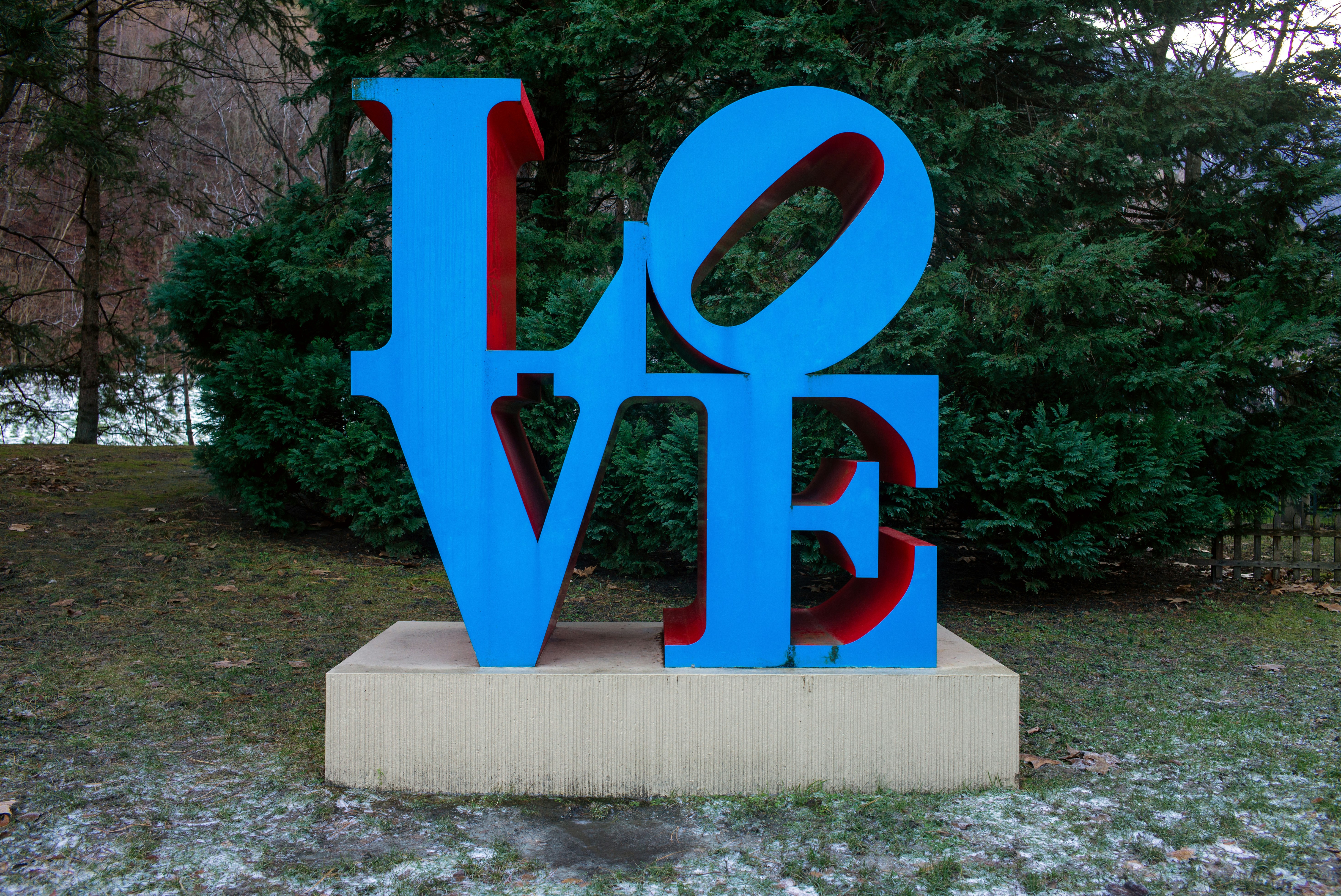 Una scultura blu e rossa di LOVE su una base di cemento in un parco
