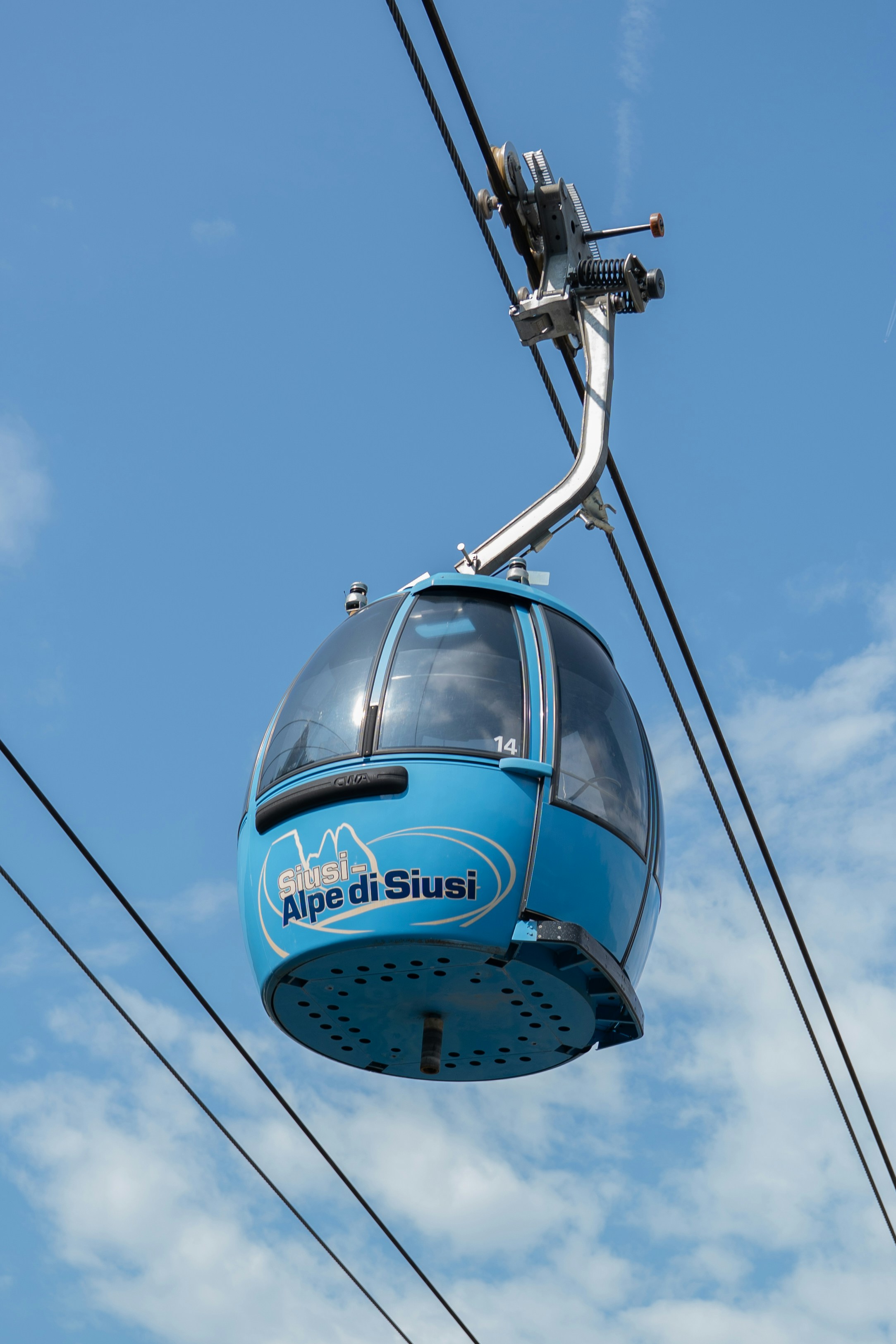 Eine blaue Seilbahn mit der Aufschrift Alpe di Siusi vor klarem blauen Himmel