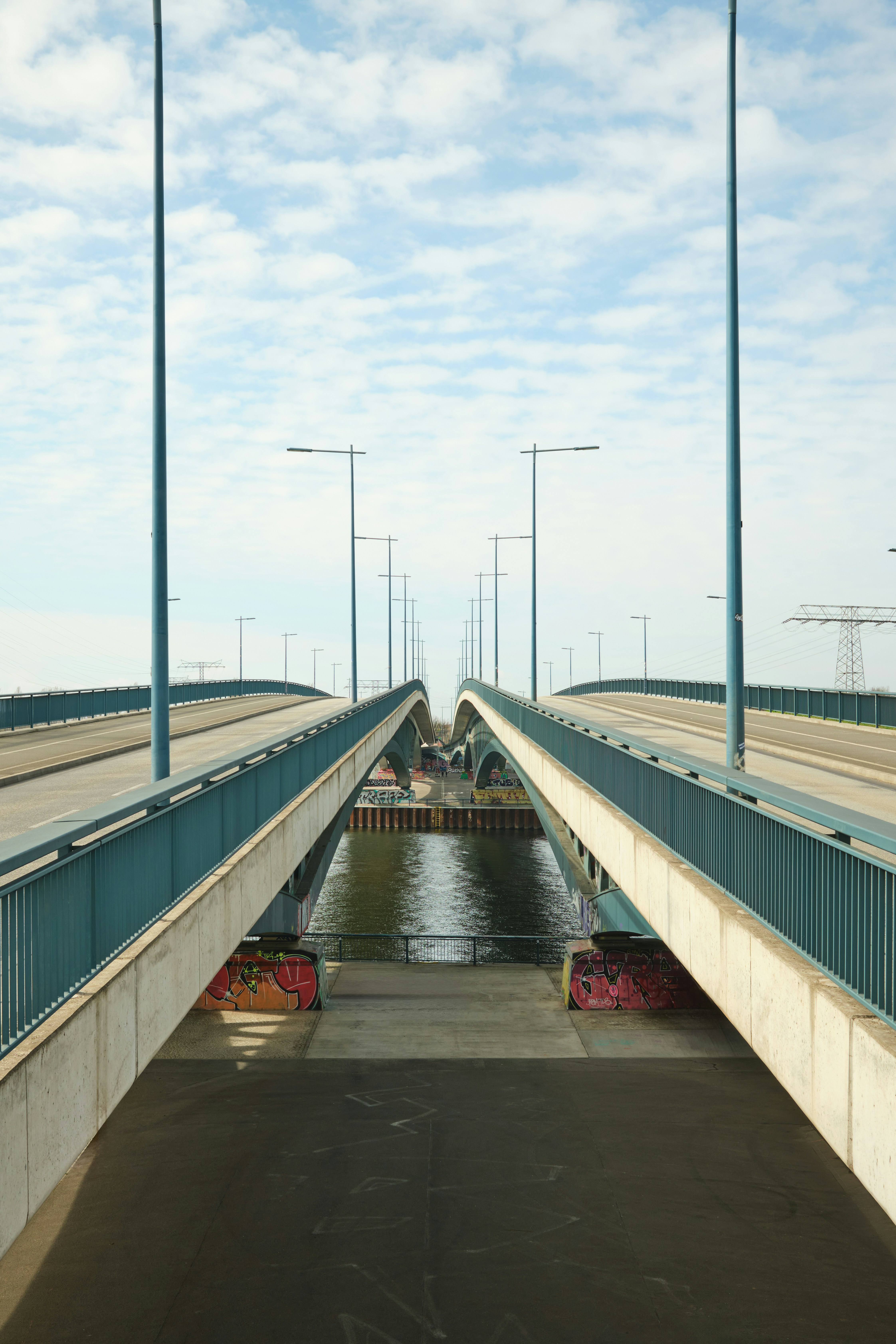 Eine geteilte Brücke mit blauen Geländern über einem Fluss unter bewölktem Himmel