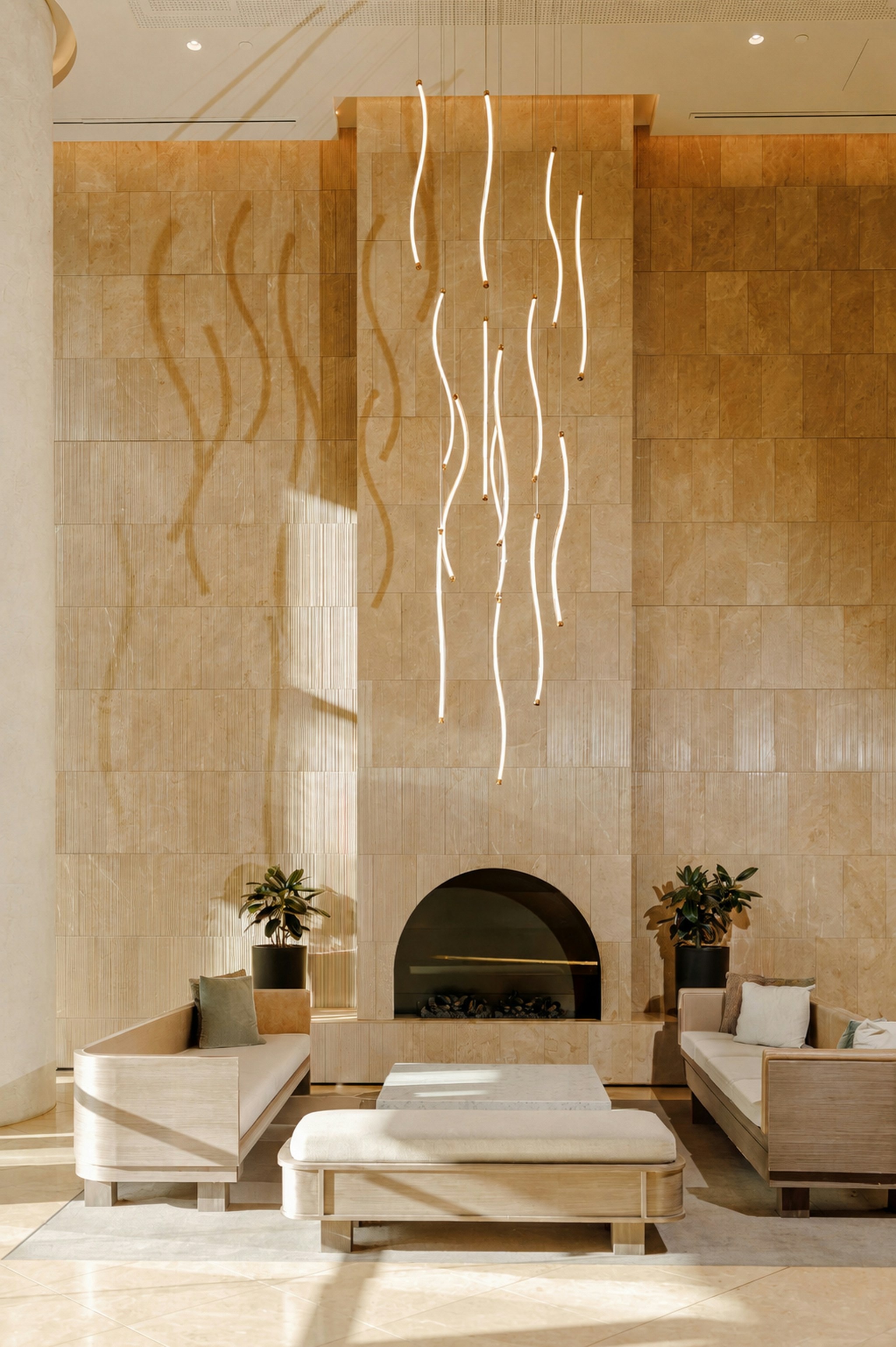 A modern lounge with stone walls, sculptural pendant lights, and sofas in Melbourne