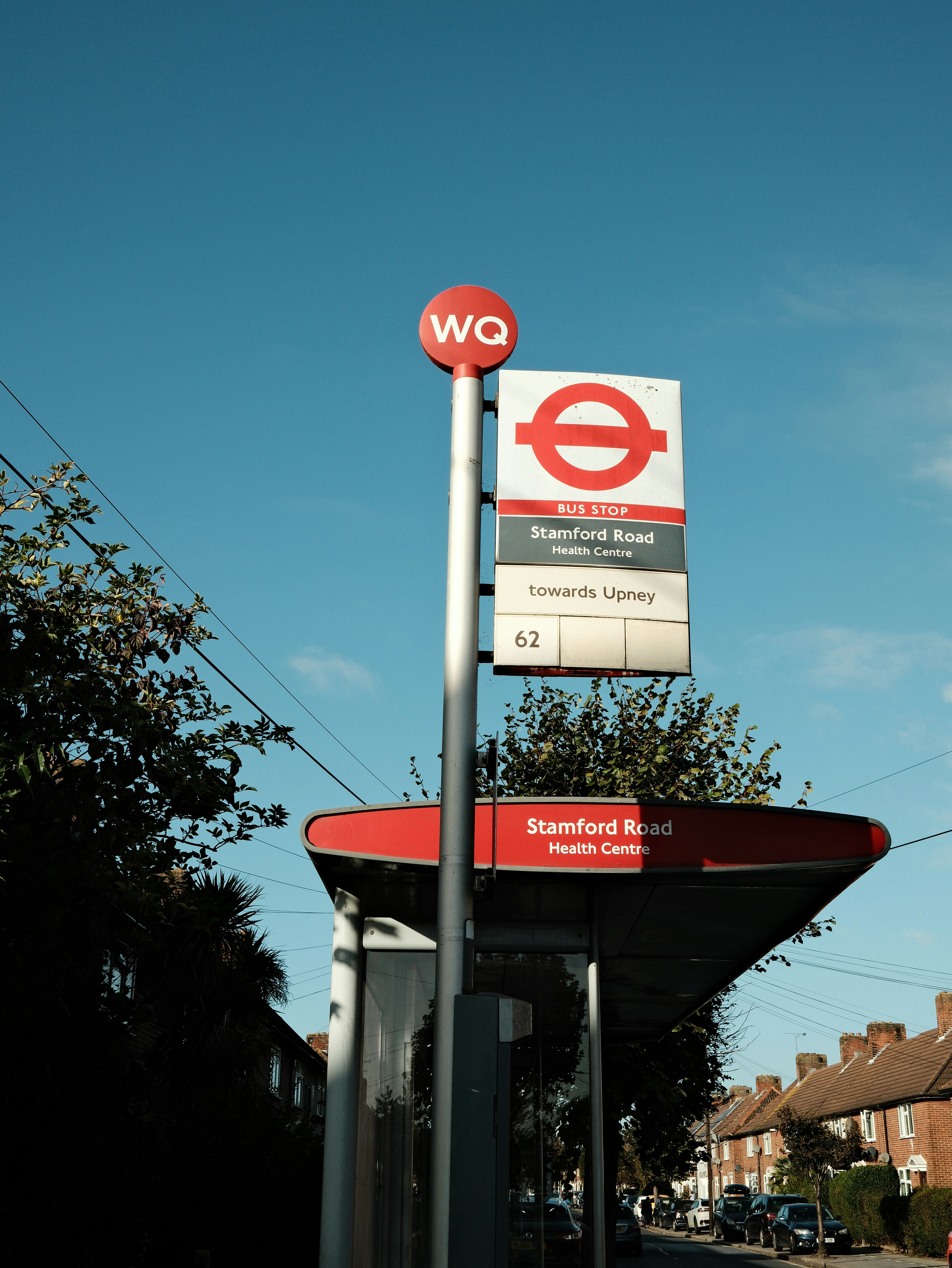 A bus stop sign reading Stamford Road Health Centre against a clear blue sky
