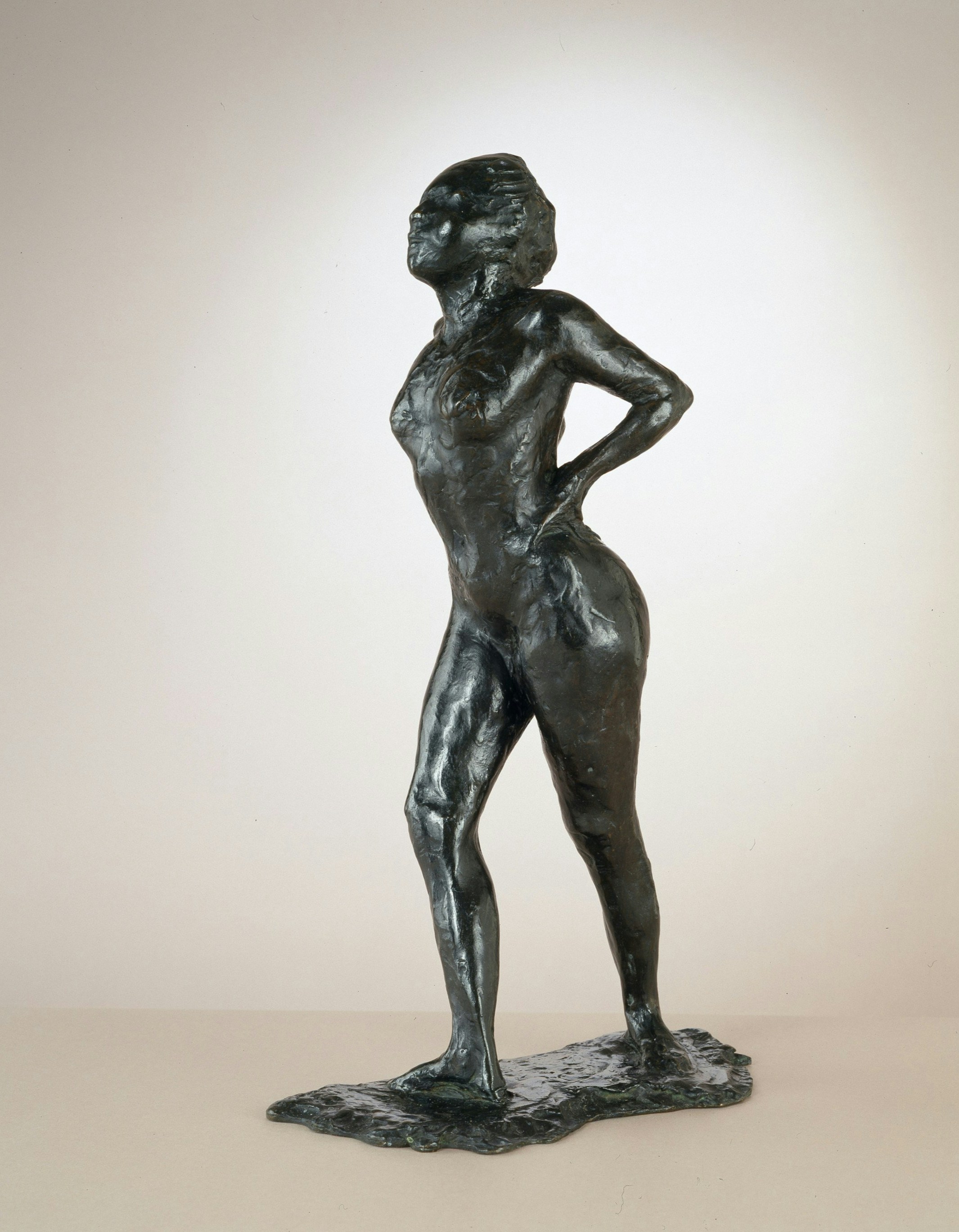 Eine dunkle Bronzeskulptur einer Frau mit den Händen in die Hüften gestemmt