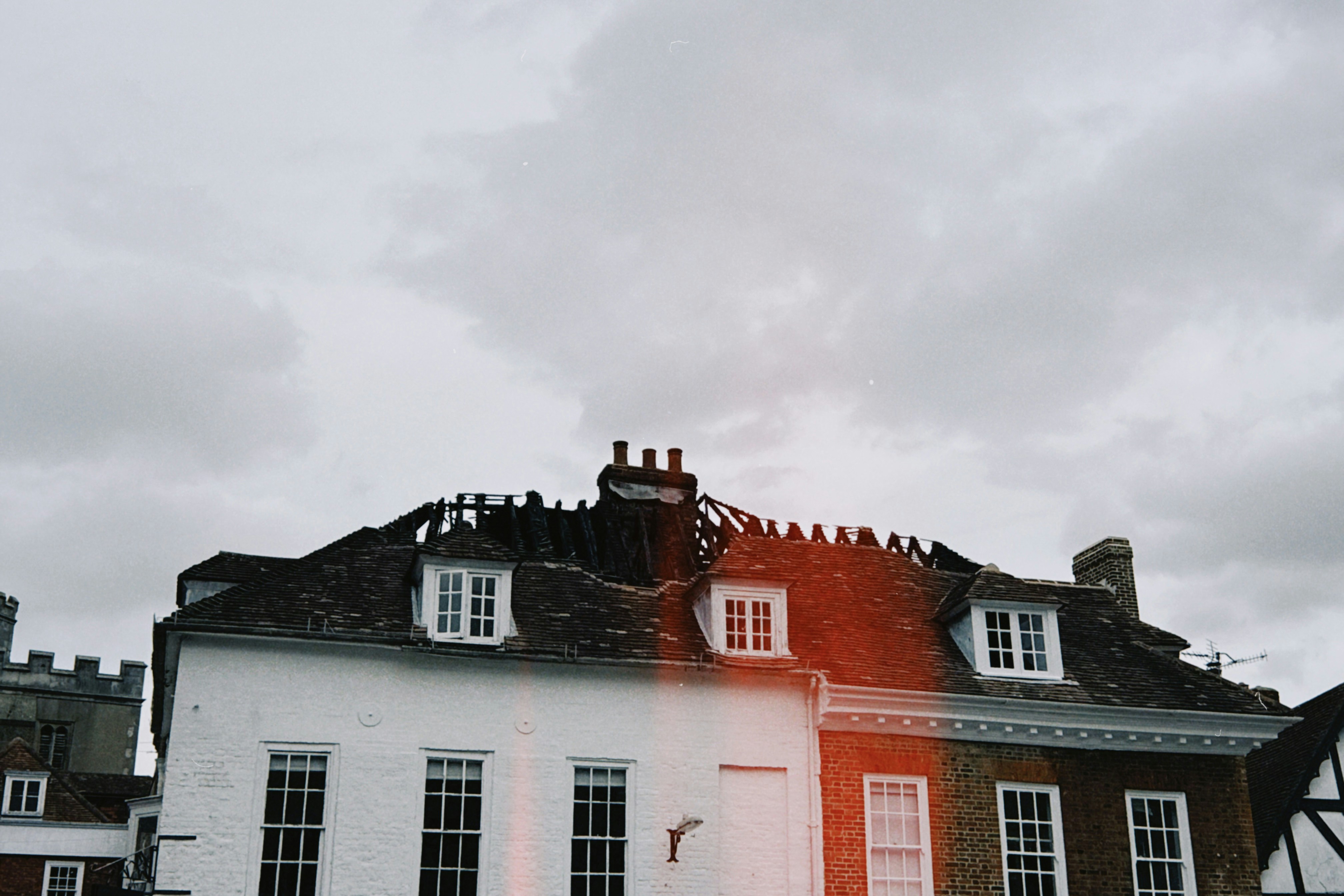 A white and brick building with dormer windows under a cloudy sky