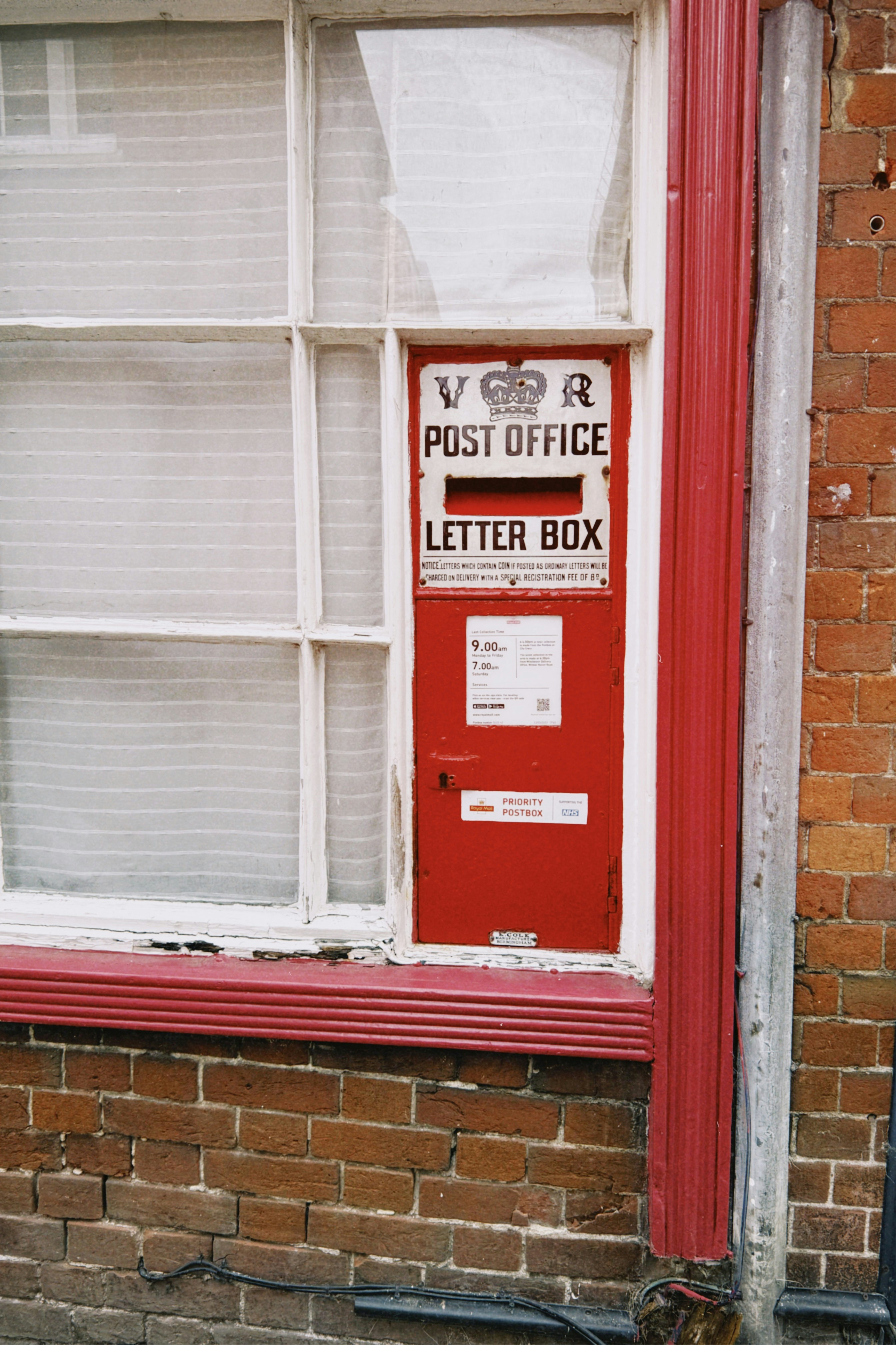 A red Victorian post office letter box set into a brick wall