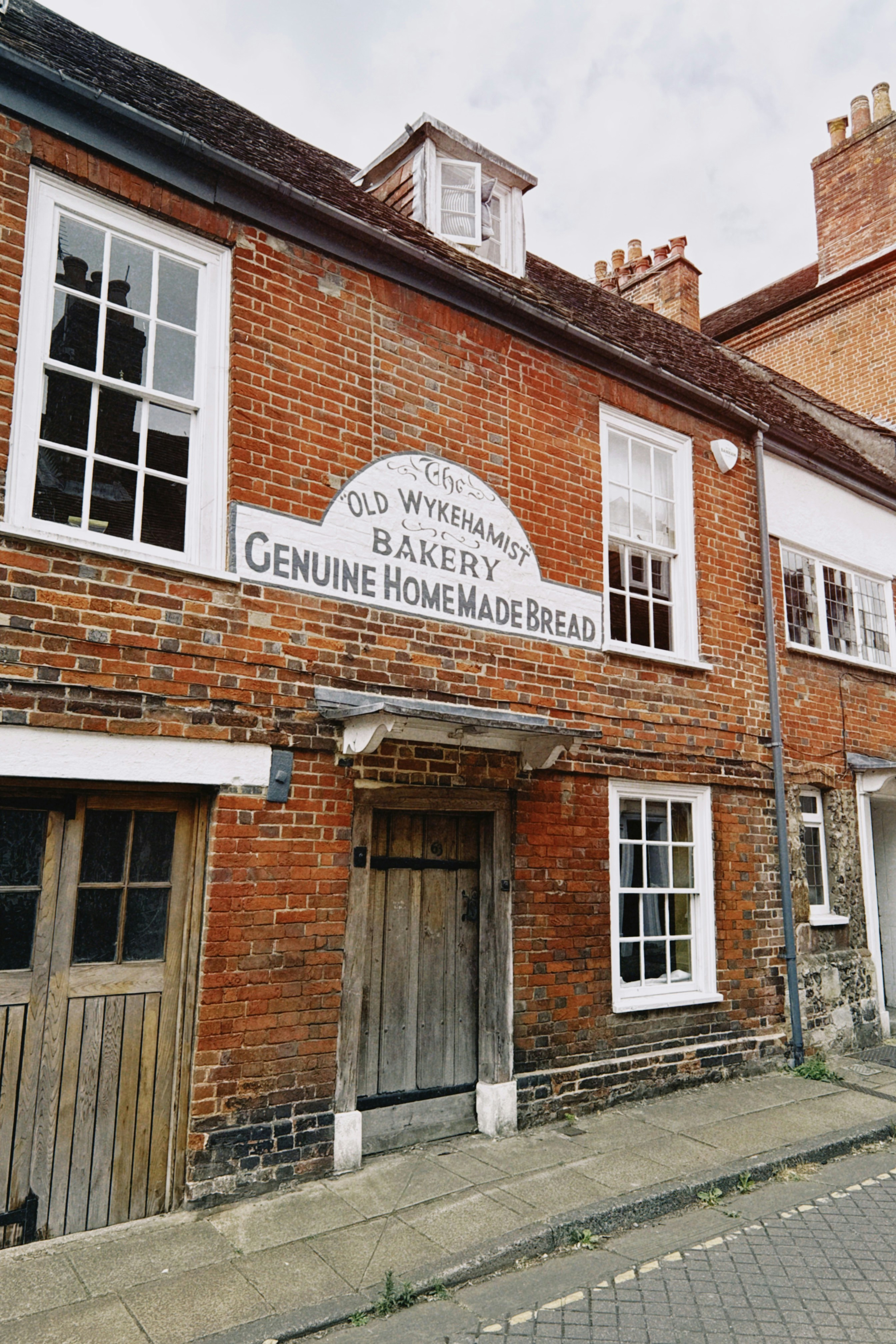 A red brick building with a sign reading The Old Wykehamist Bakery Genuine Homemade Bread