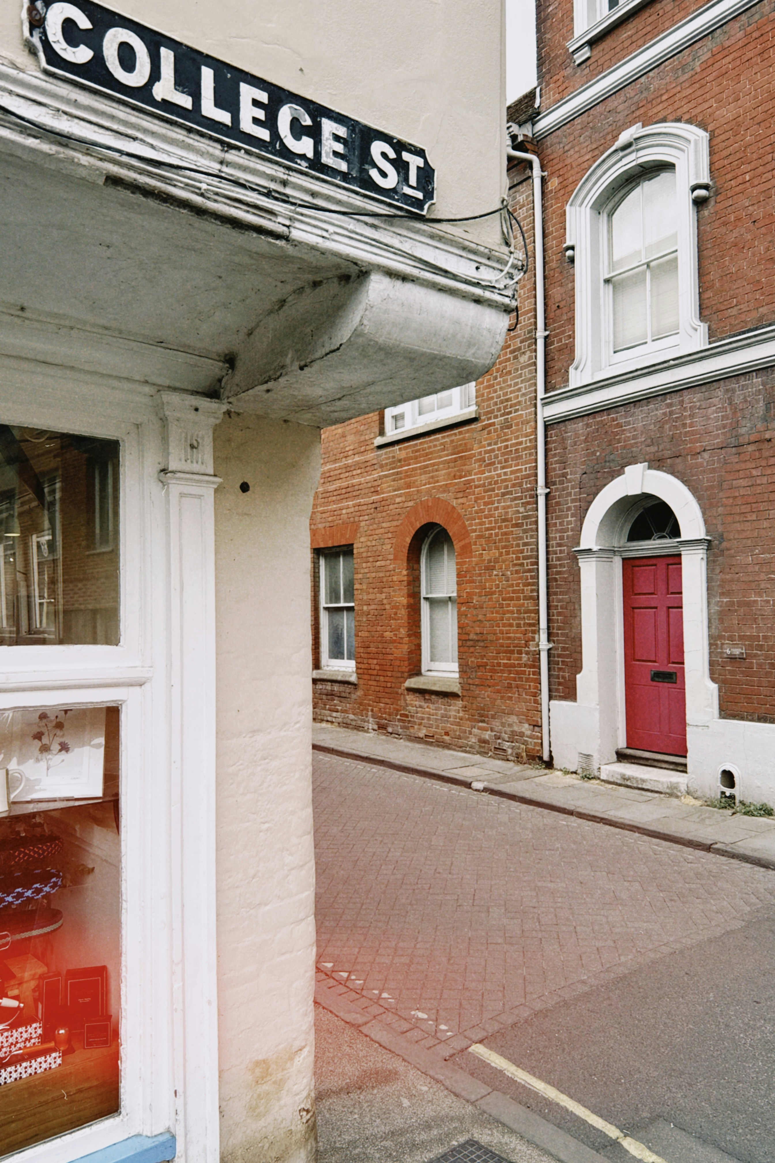 A street sign reading COLLEGE ST on a corner building with a red door
