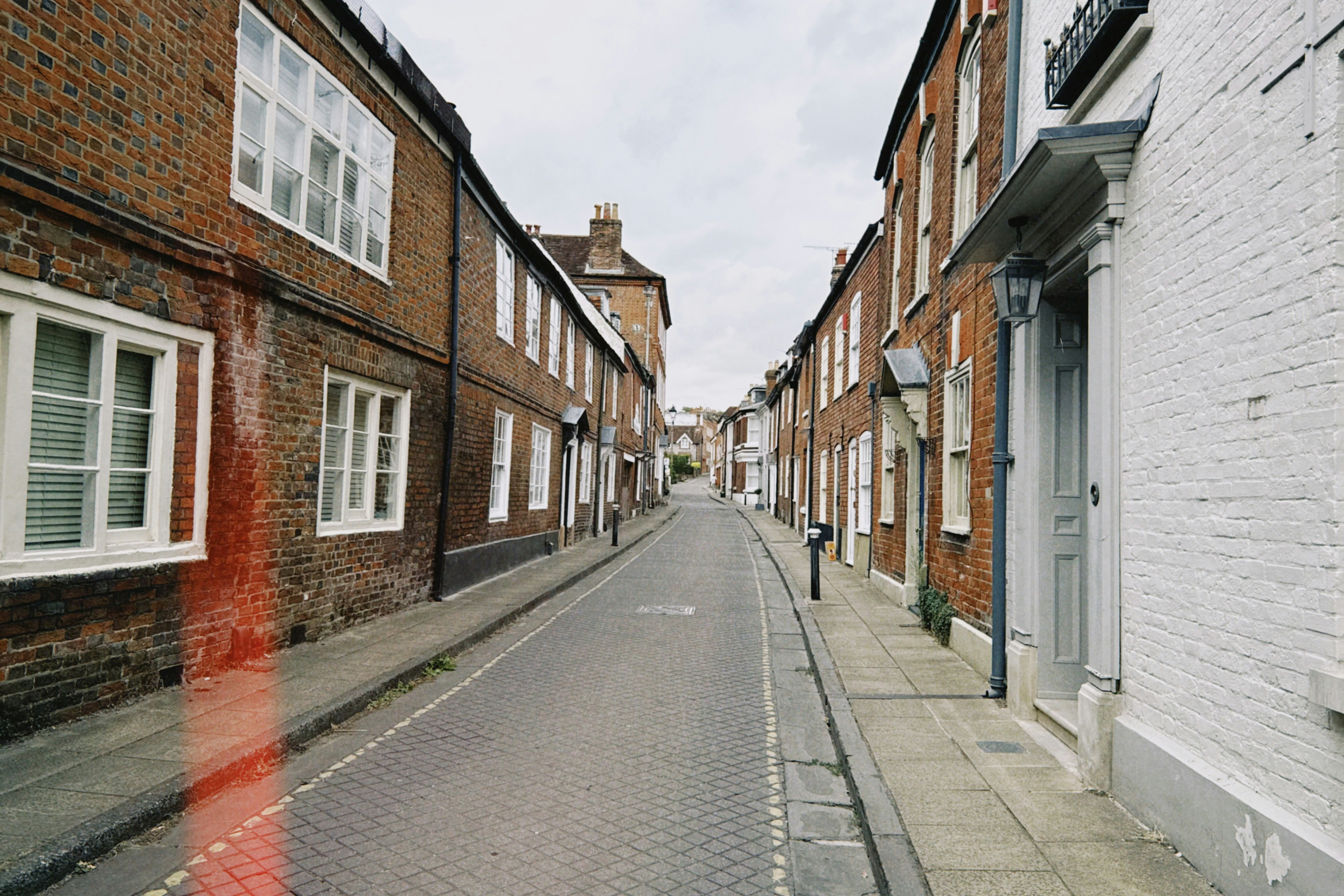 A narrow street lined with historic brick buildings and white window frames