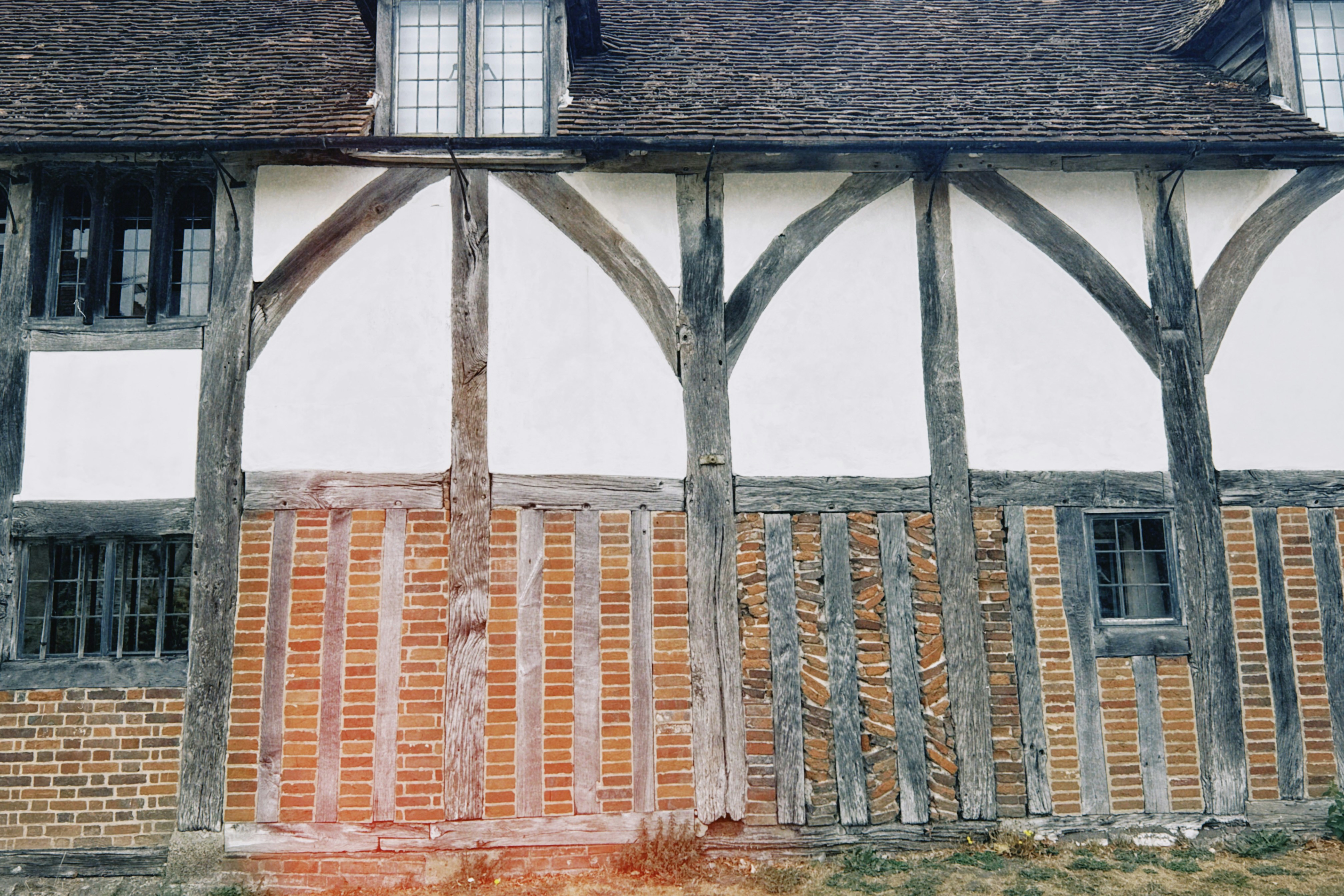 Timber-framed listed building with white plaster, red brick and leaded glass windows