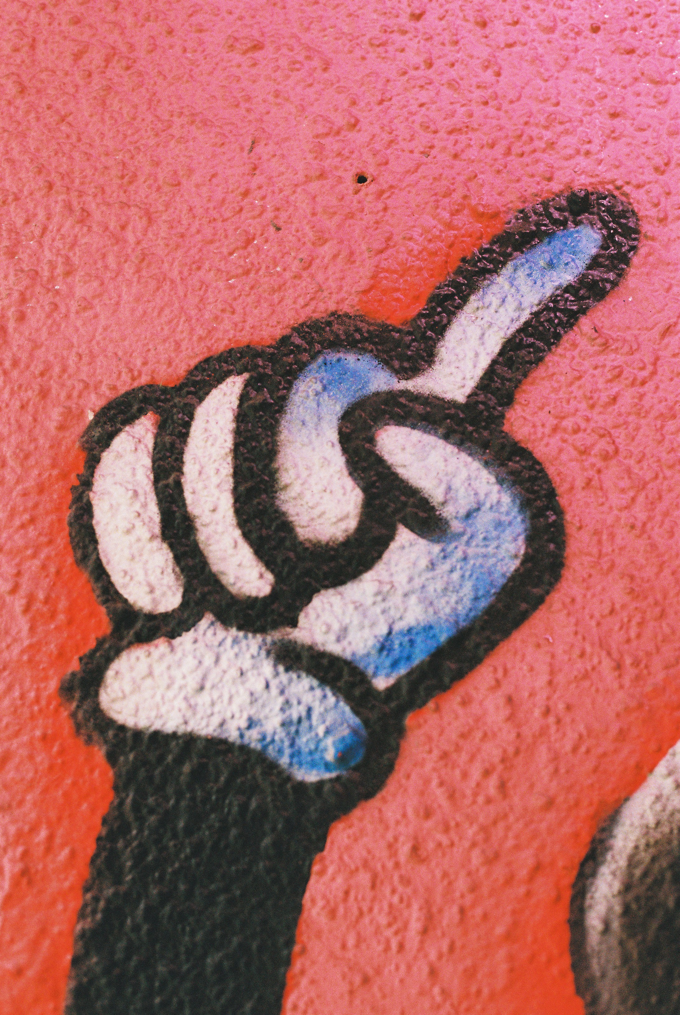 A stylized hand with a raised index finger painted on a textured red wall