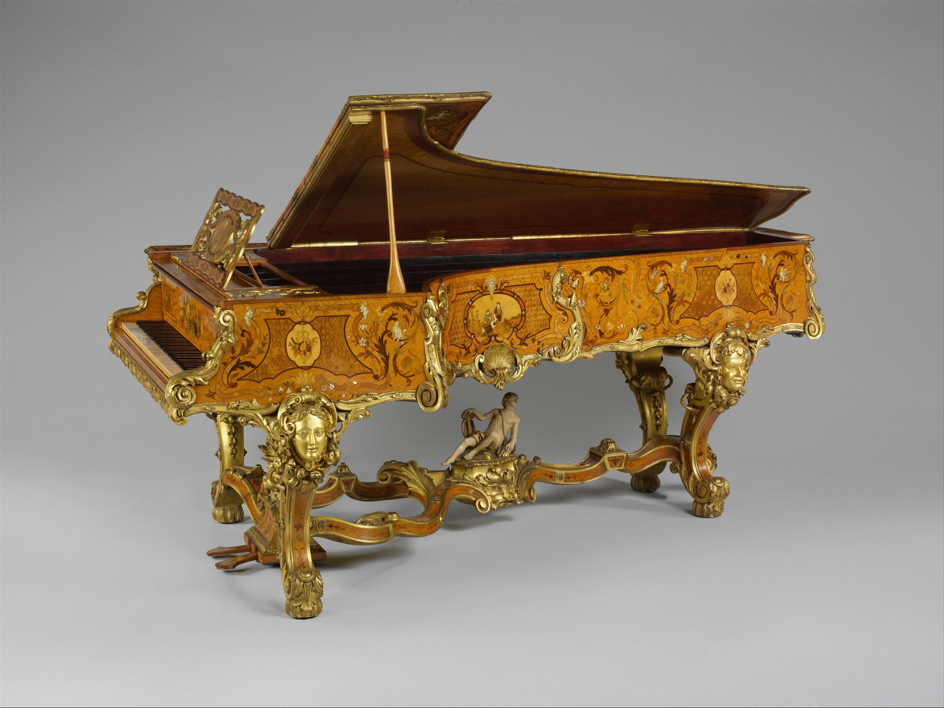 An ornate grand piano with intricate wood marquetry and gilded bronze sculptural legs