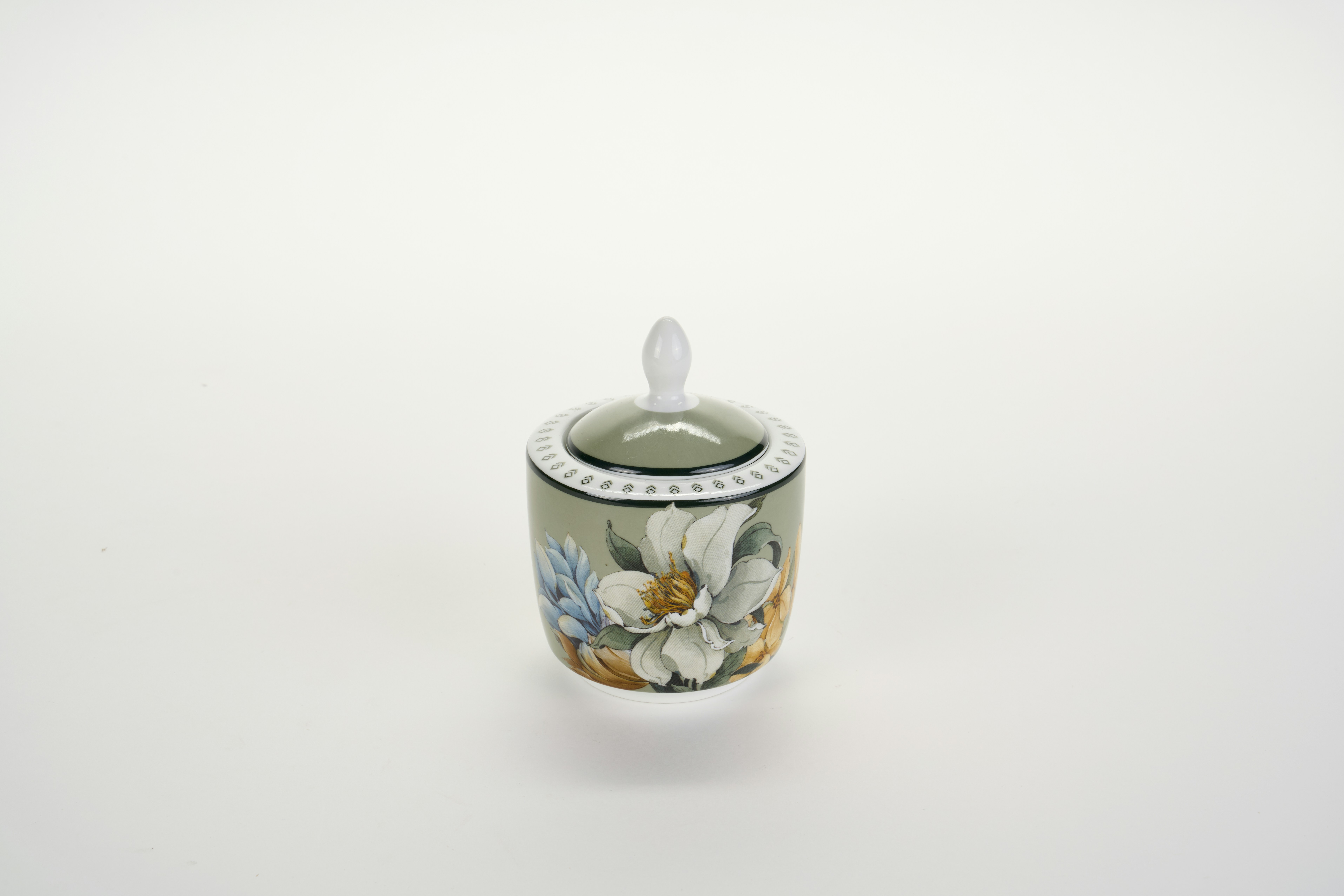 A small ceramic sugar bowl with a lid and floral pattern on white