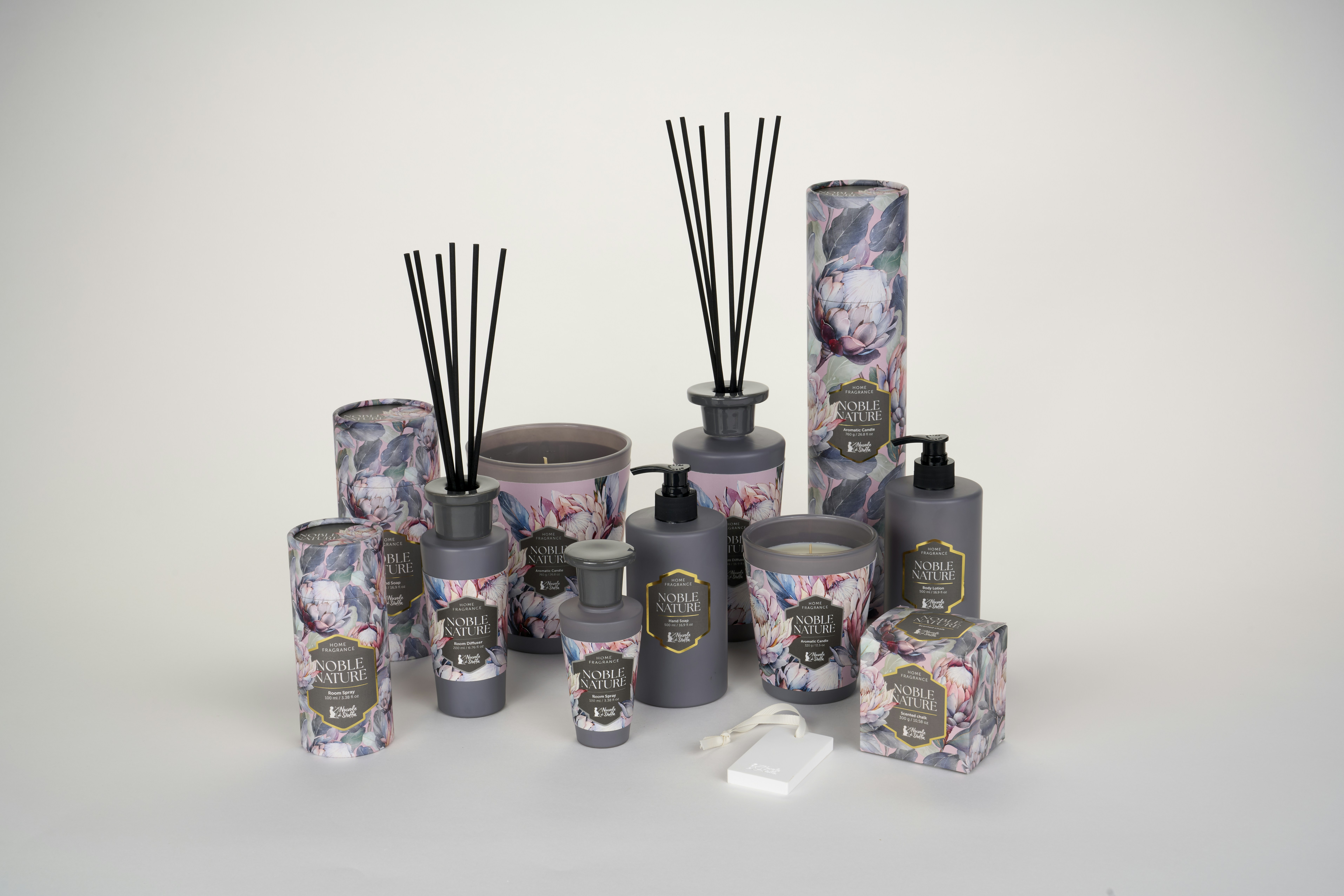 A collection of grey home fragrance products with floral packaging on a white surface