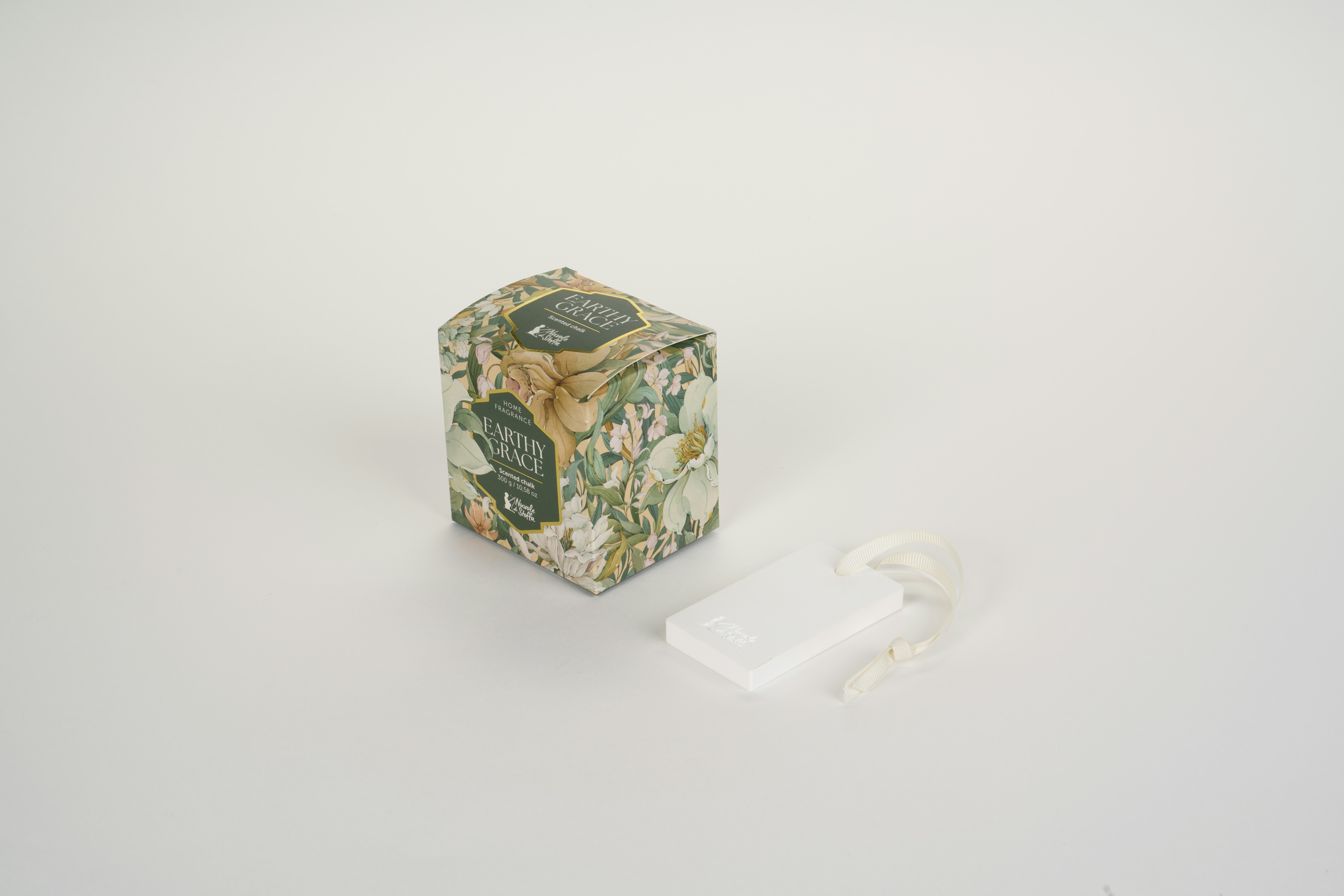 A floral patterned box beside a white rectangular scented chalk with a ribbon