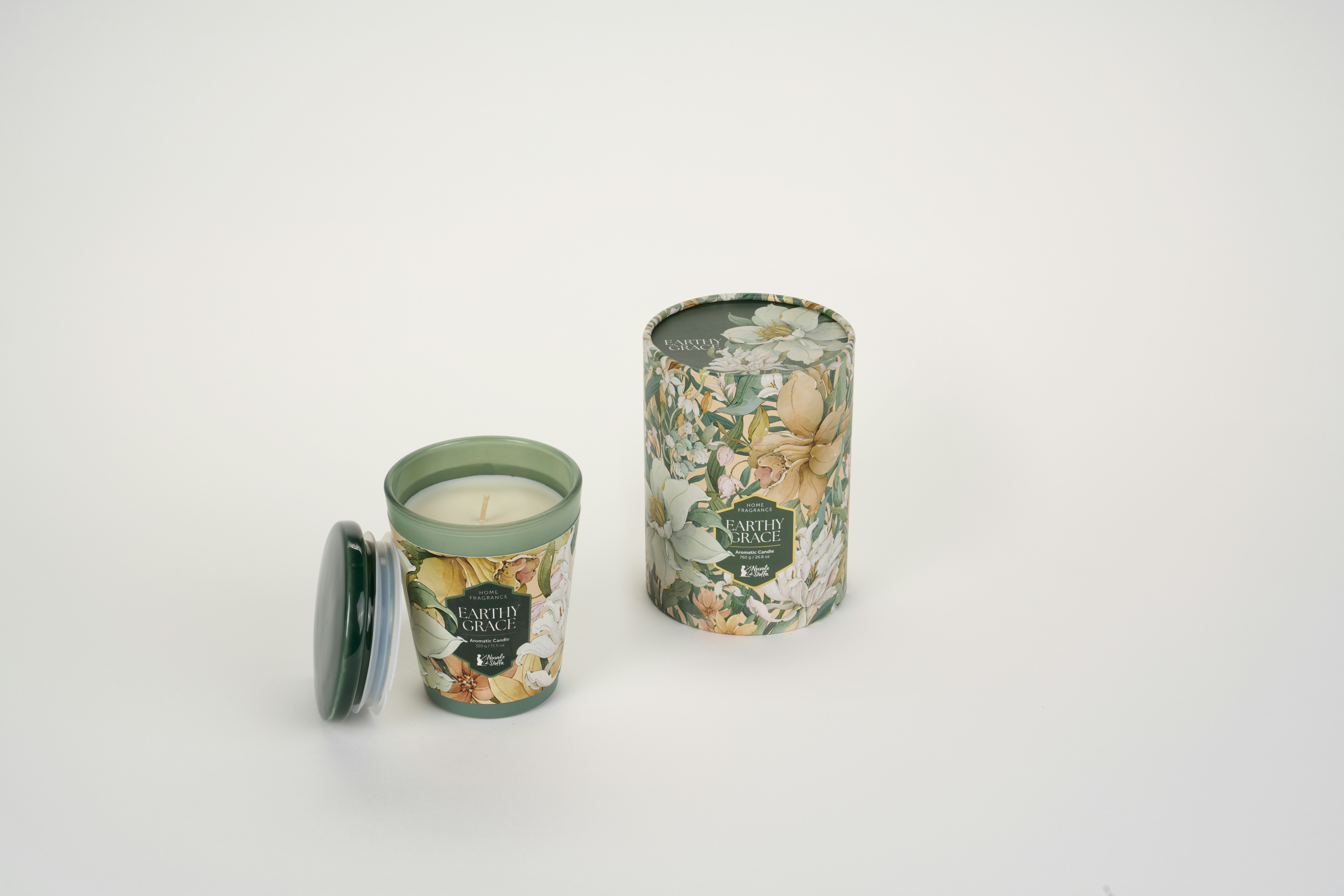 A scented candle in a green glass jar beside its floral patterned cylindrical box
