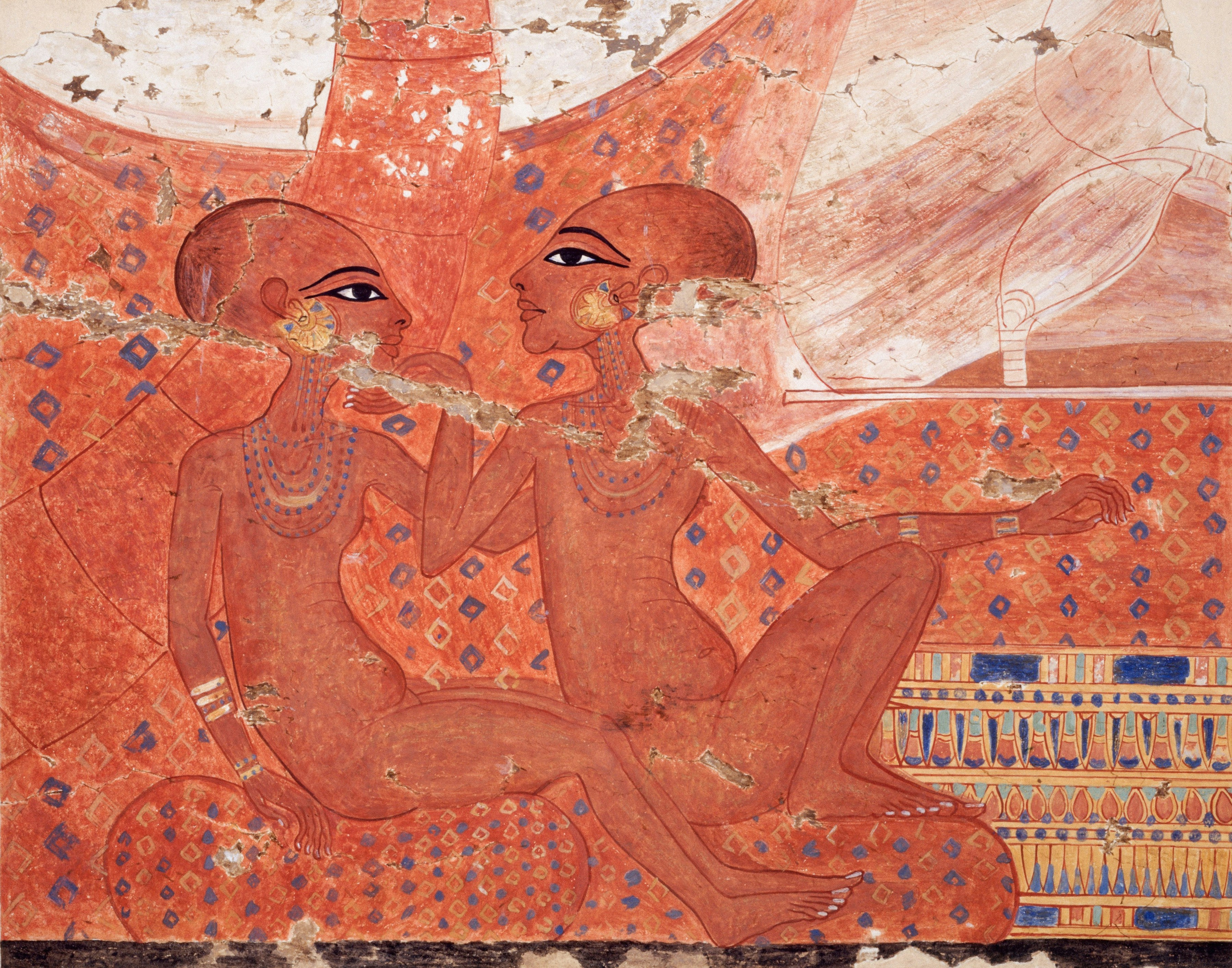 Two people with shaved heads wearing jewelry in an ancient Egyptian wall mural