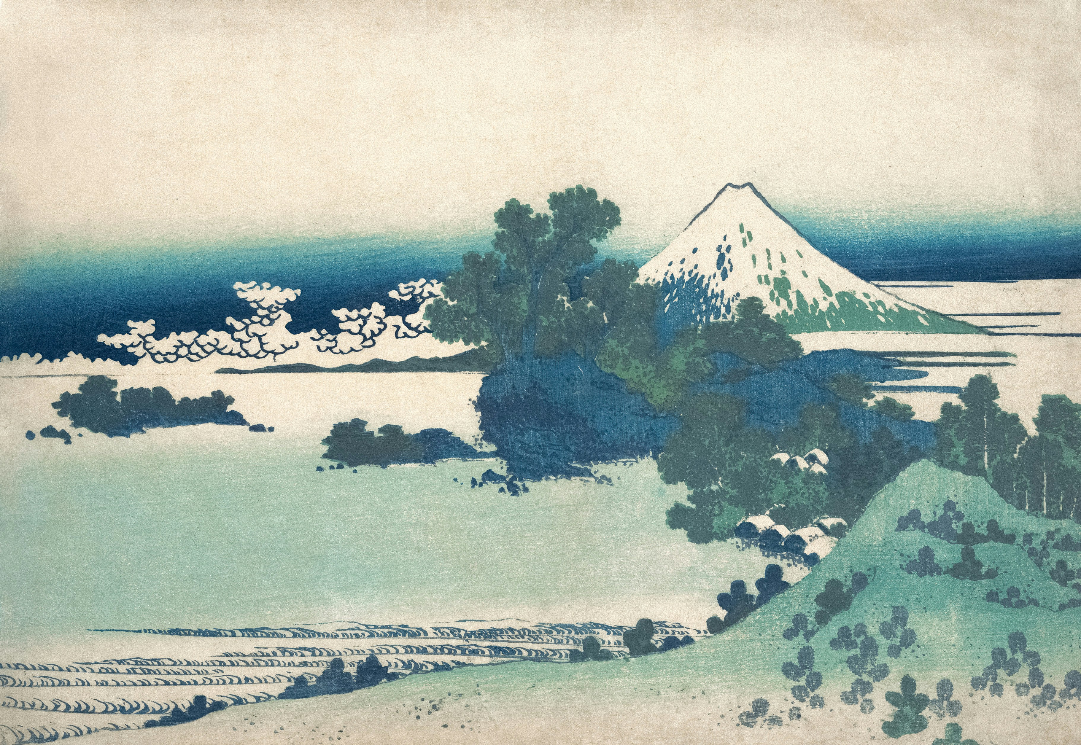 Mount Fuji rising above a coastal landscape with trees and small houses