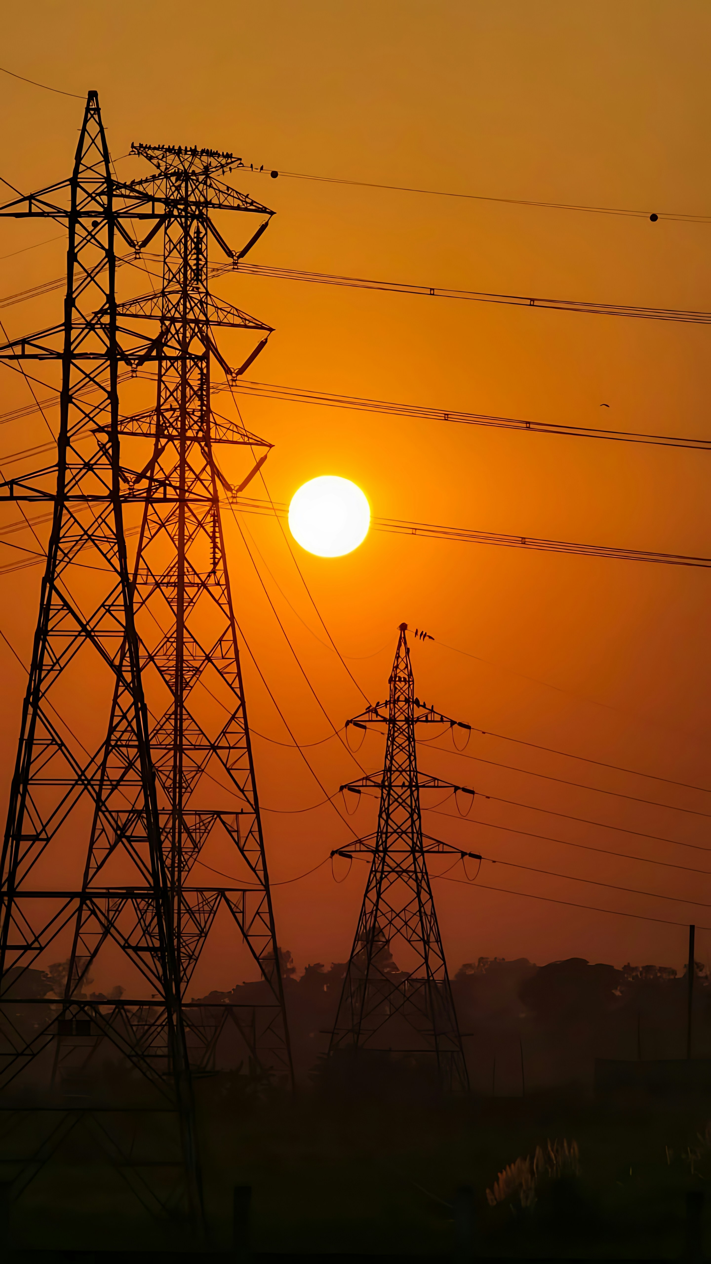 Deux tours de transmission électrique se découpaient sur un ciel orange vif avec un soleil bas