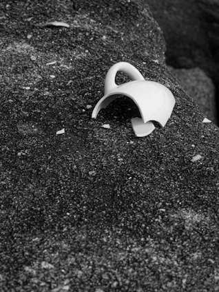 A broken white ceramic mug on a rough dark stone surface