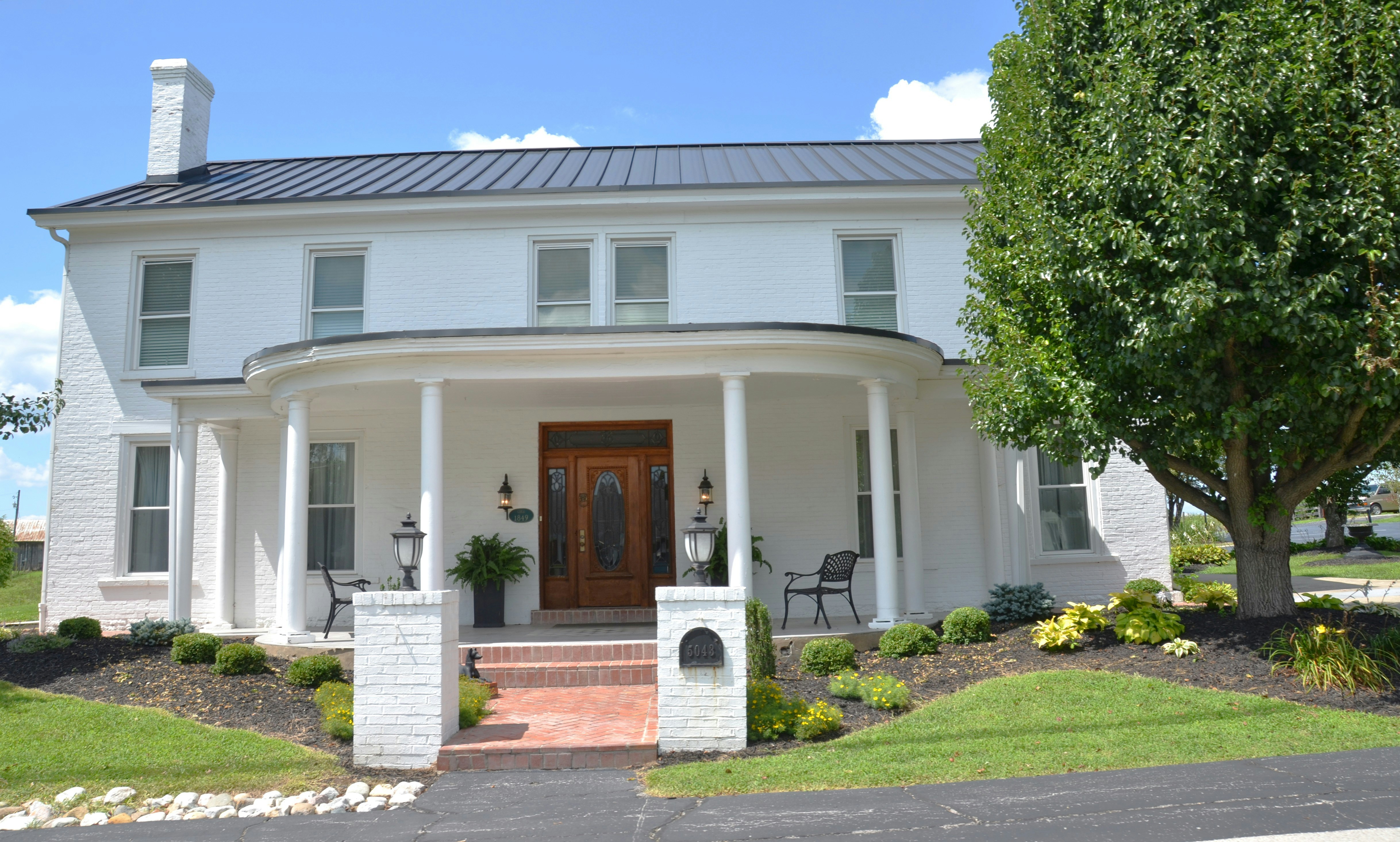 Grand white brick home with a curved columned porch