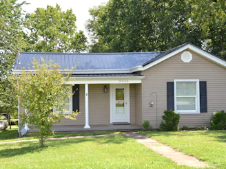A single story house with beige siding and a dark metal roof