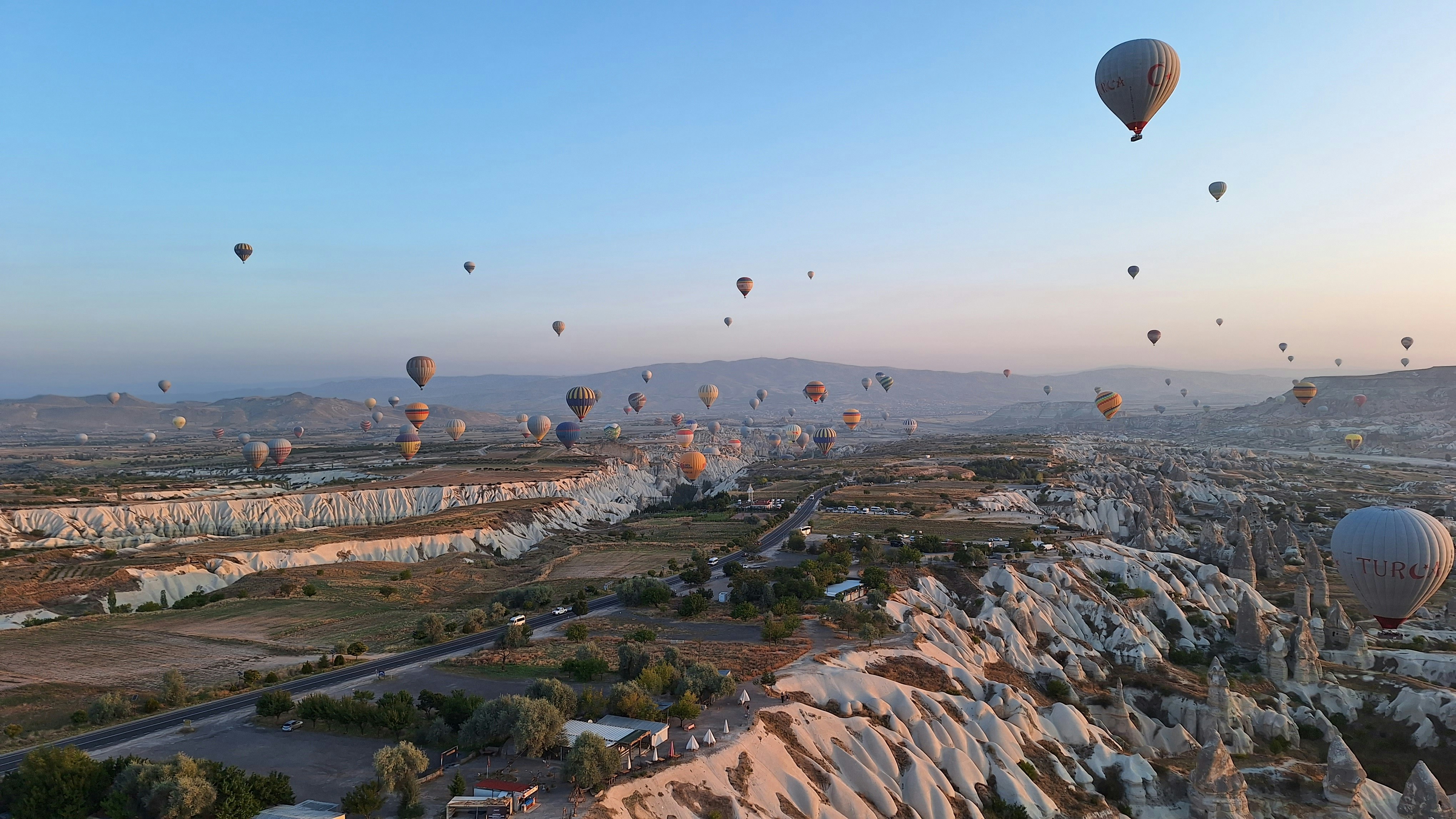 Dozens of balloons drifting over the Goreme valleys in Cappadocia