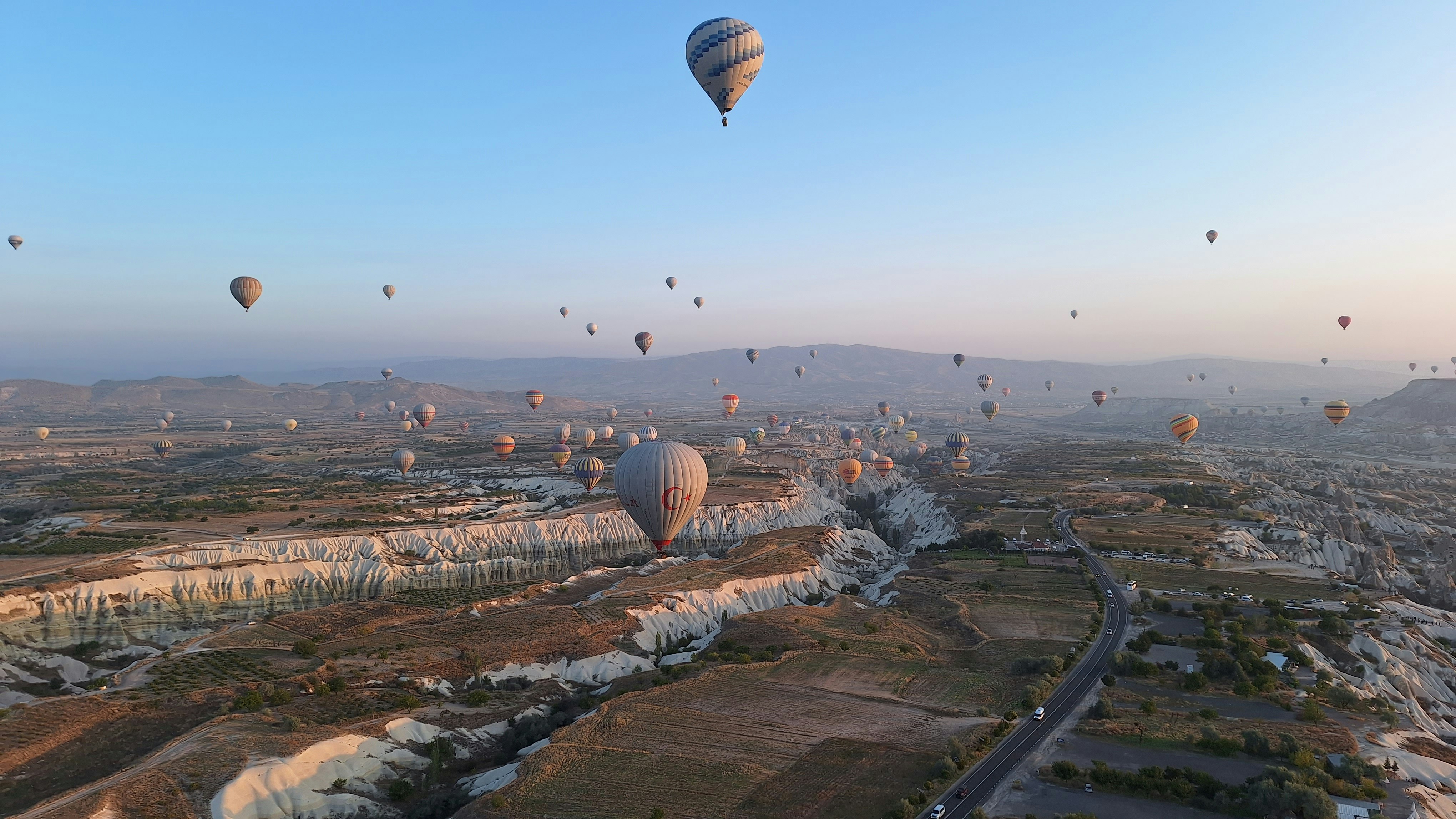 Many hot air balloons floating over the rocky landscape of Cappadocia in Turkey