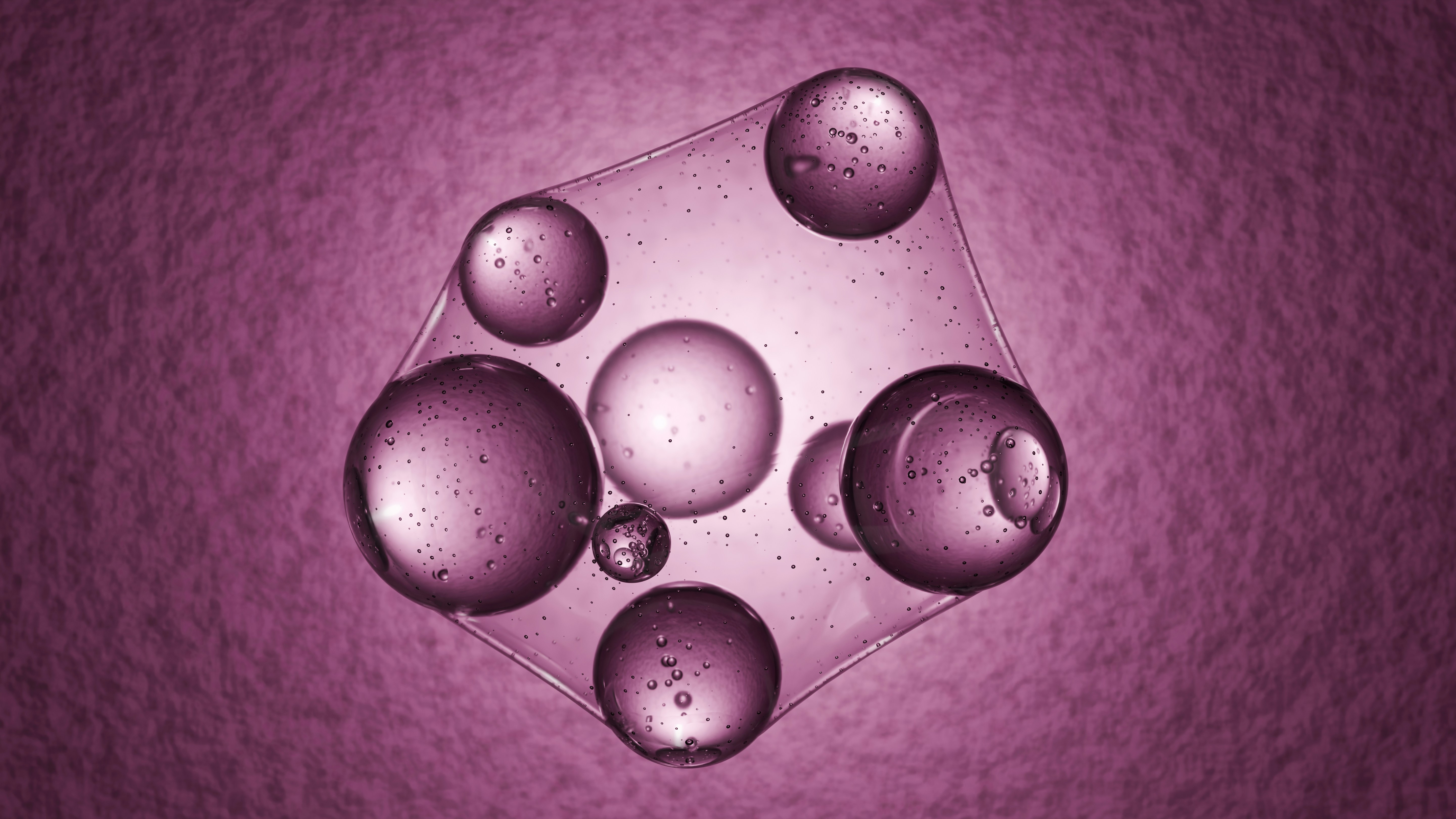 Clear liquid spheres suspended in a purple gel against a textured background