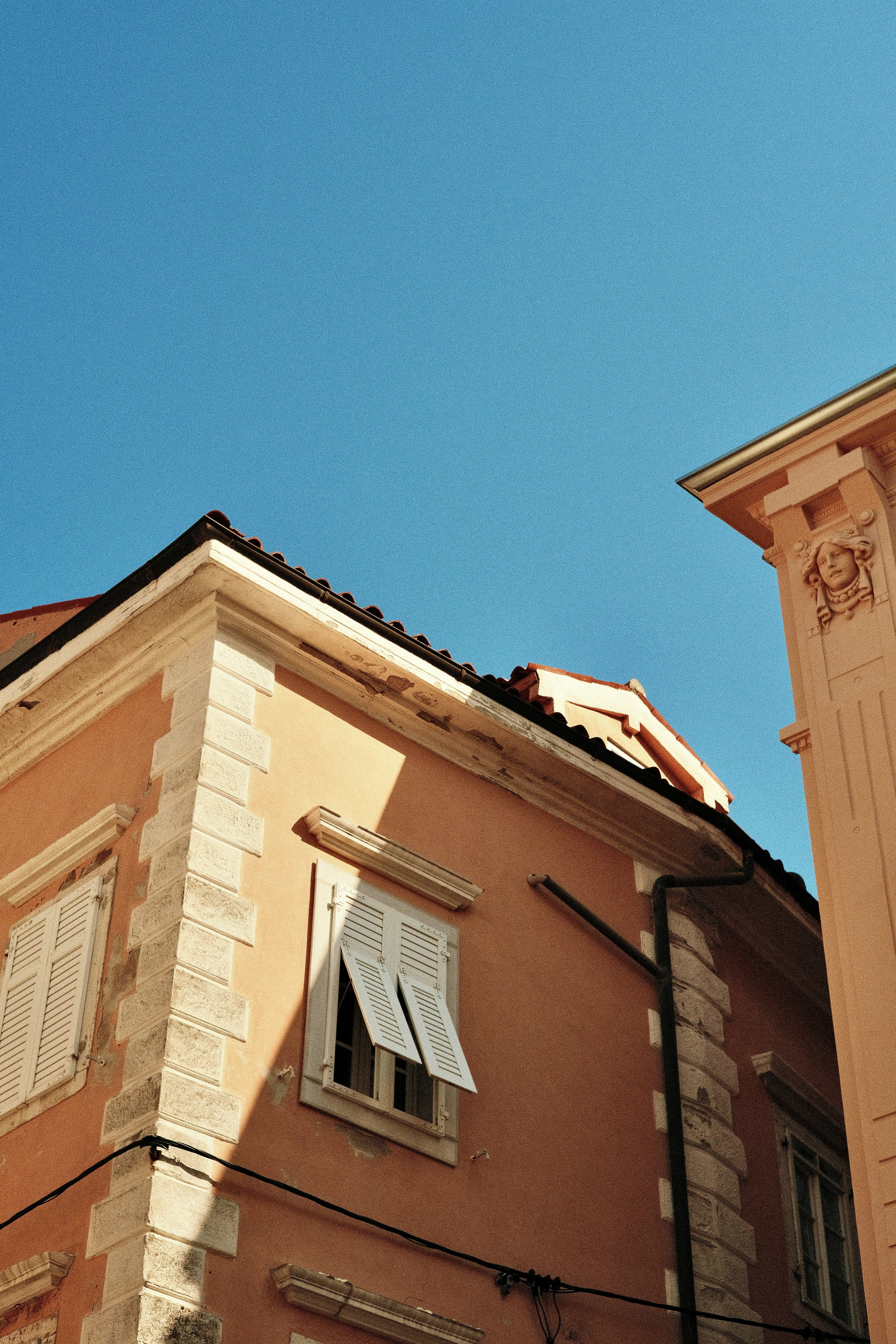 Peach colored buildings with white shutters under a clear blue sky