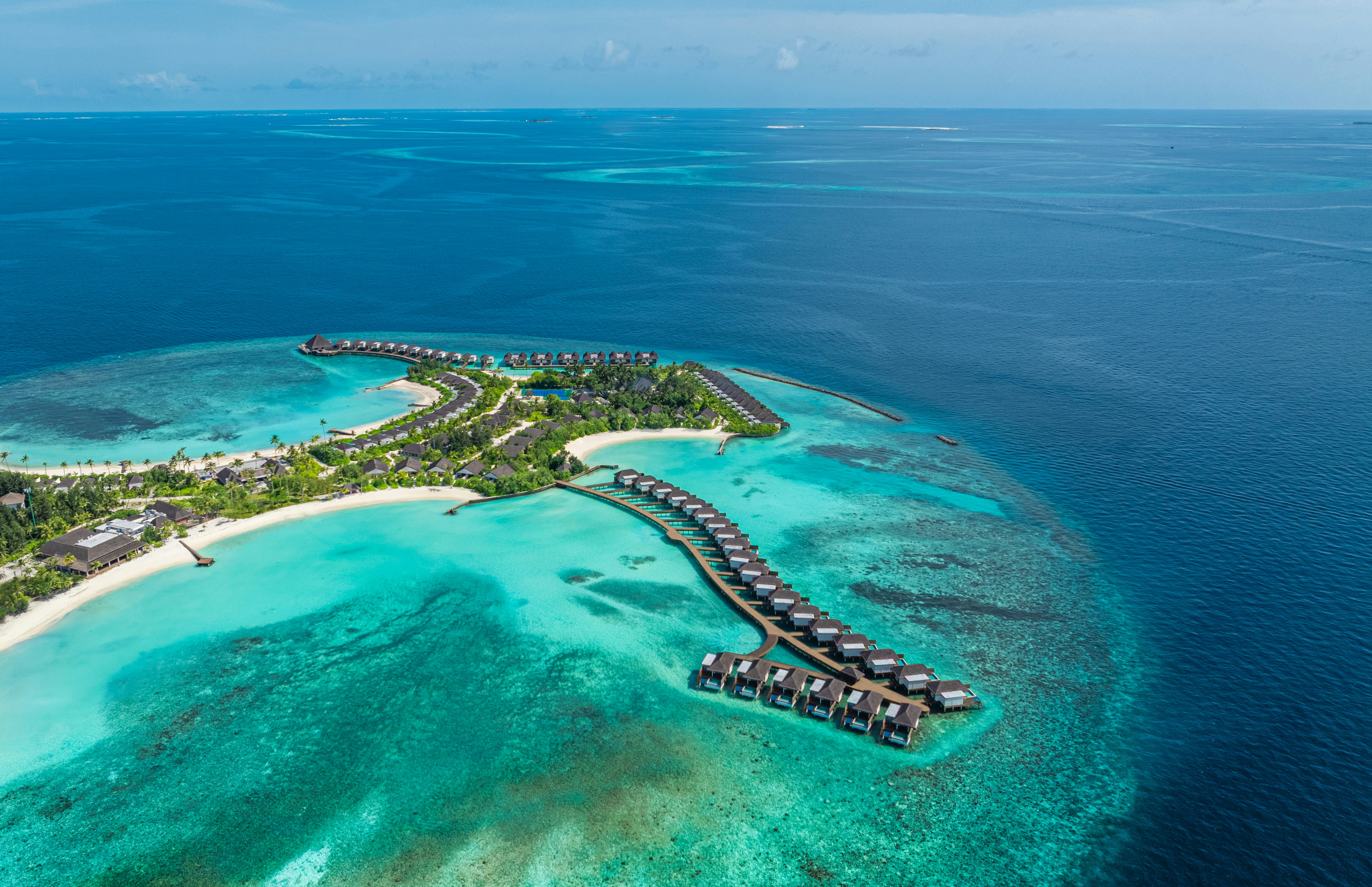 An aerial view of a tropical island resort with overwater bungalows in the Maldives