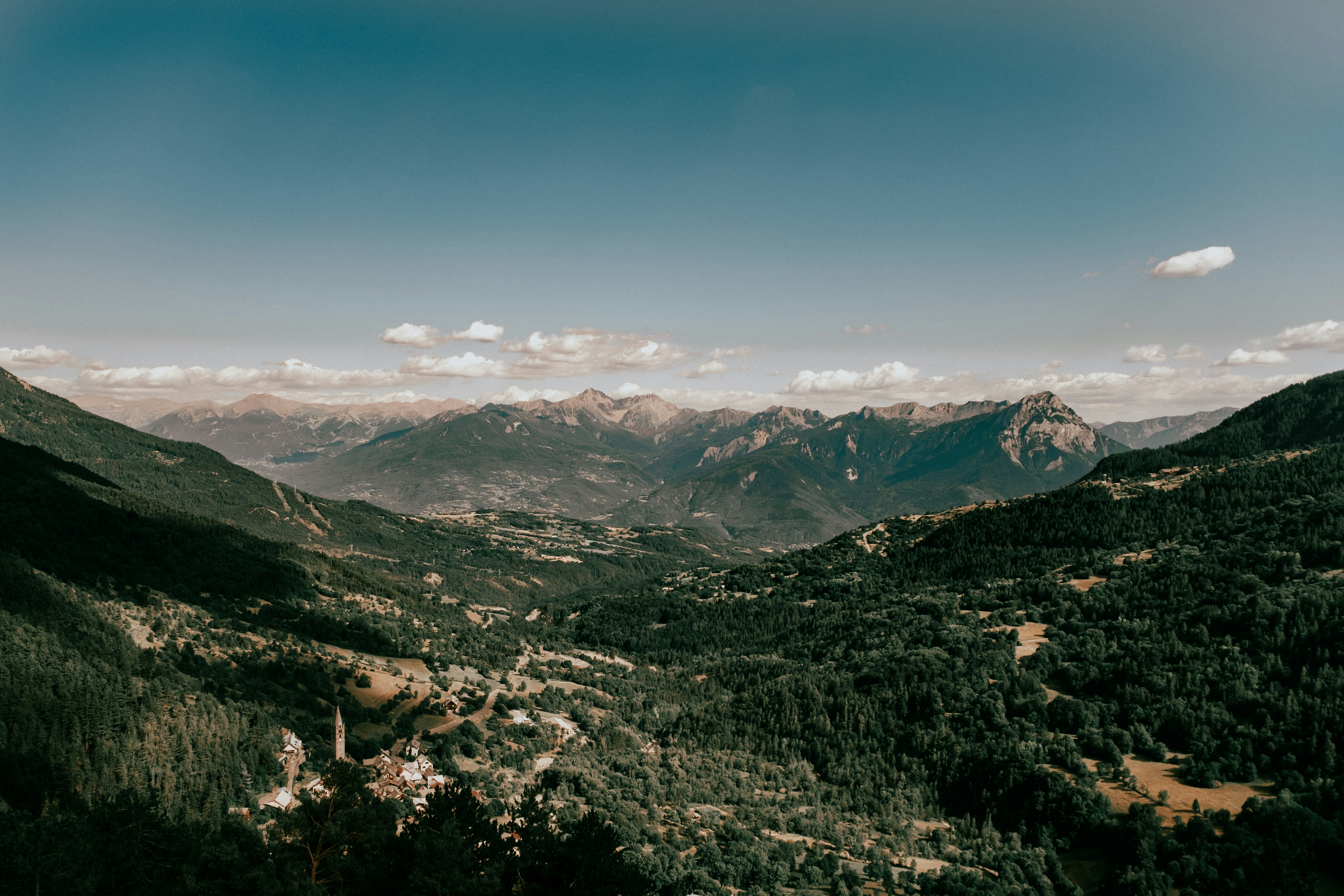 A small village with a church spire in a deep green mountain valley