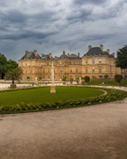 The Luxembourg Palace and its manicured gardens under a cloudy sky in Paris