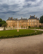 The Luxembourg Palace and its manicured gardens under a cloudy sky in Paris