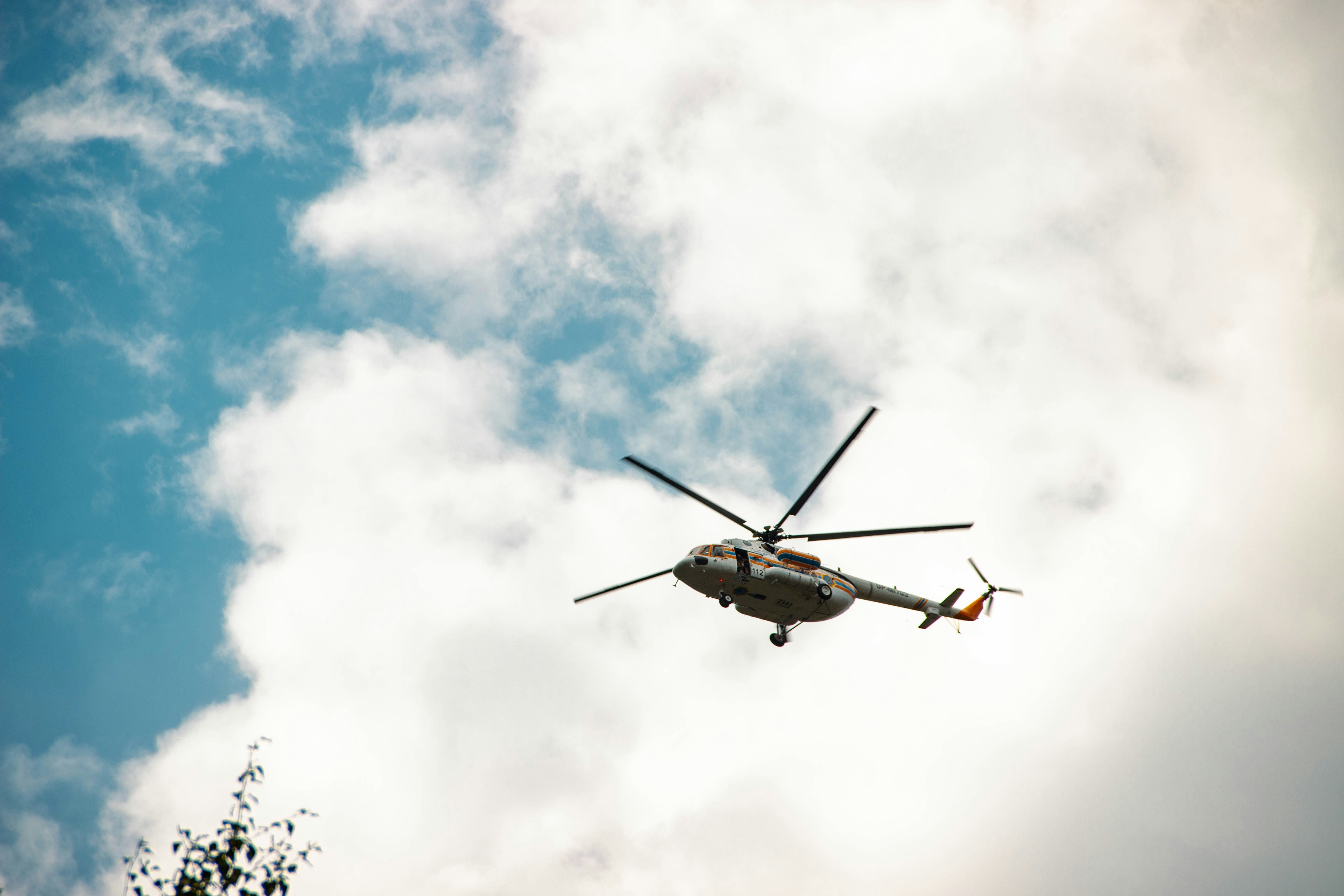 A helicopter flying through a blue sky with white clouds