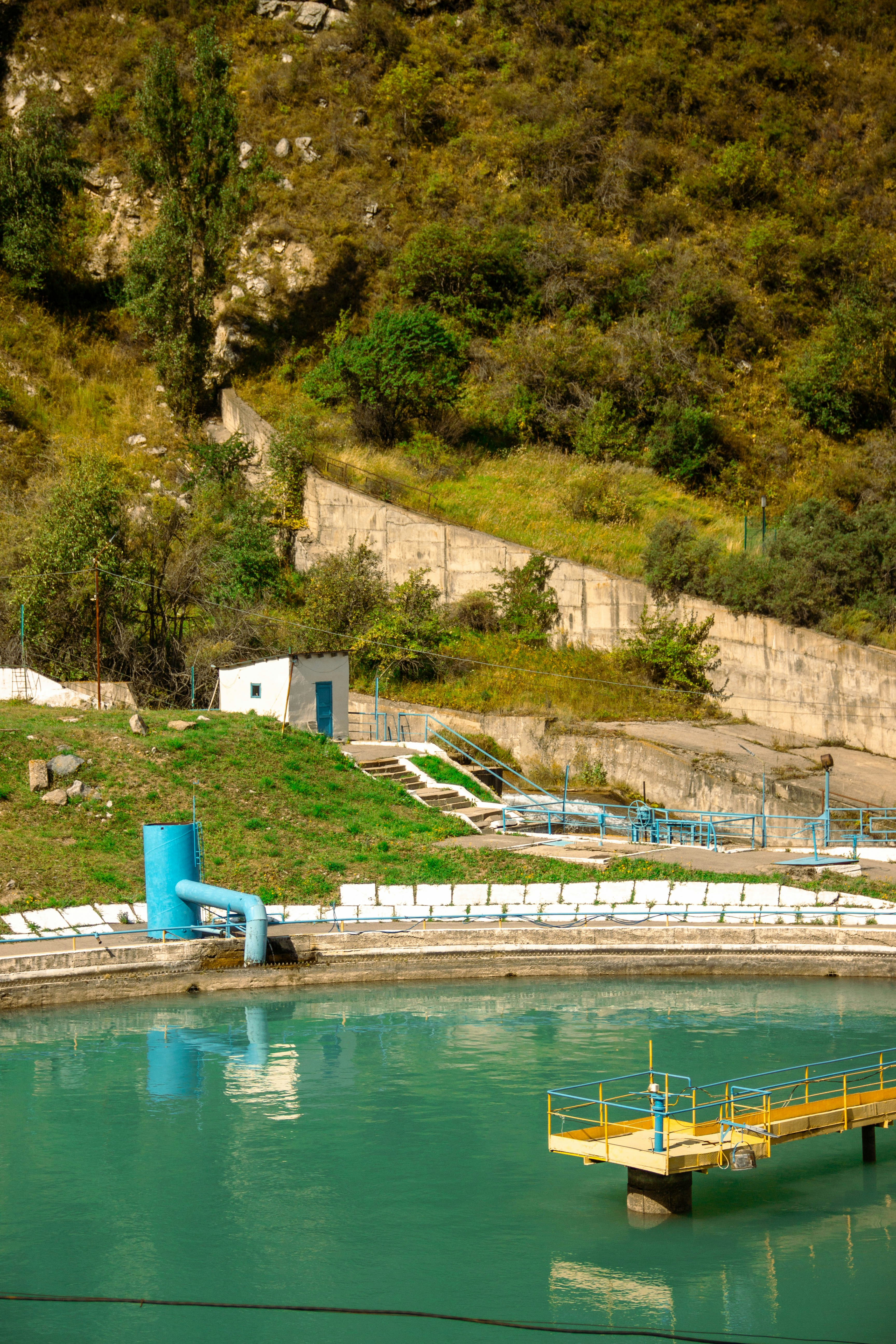 A turquoise water reservoir with a yellow metal platform and a blue pipe