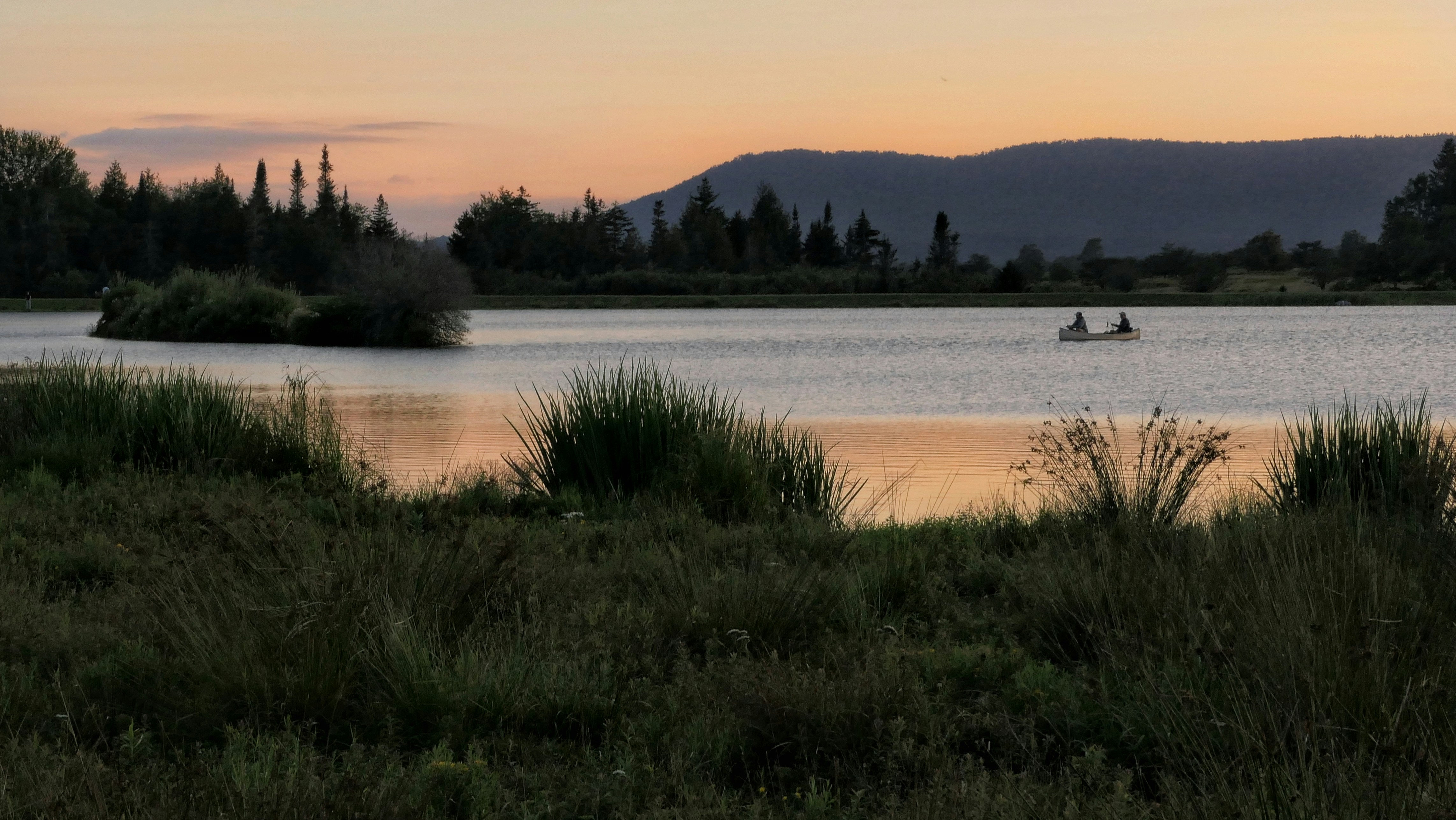 Due persone in canoa su un lago durante l'ora d'oro