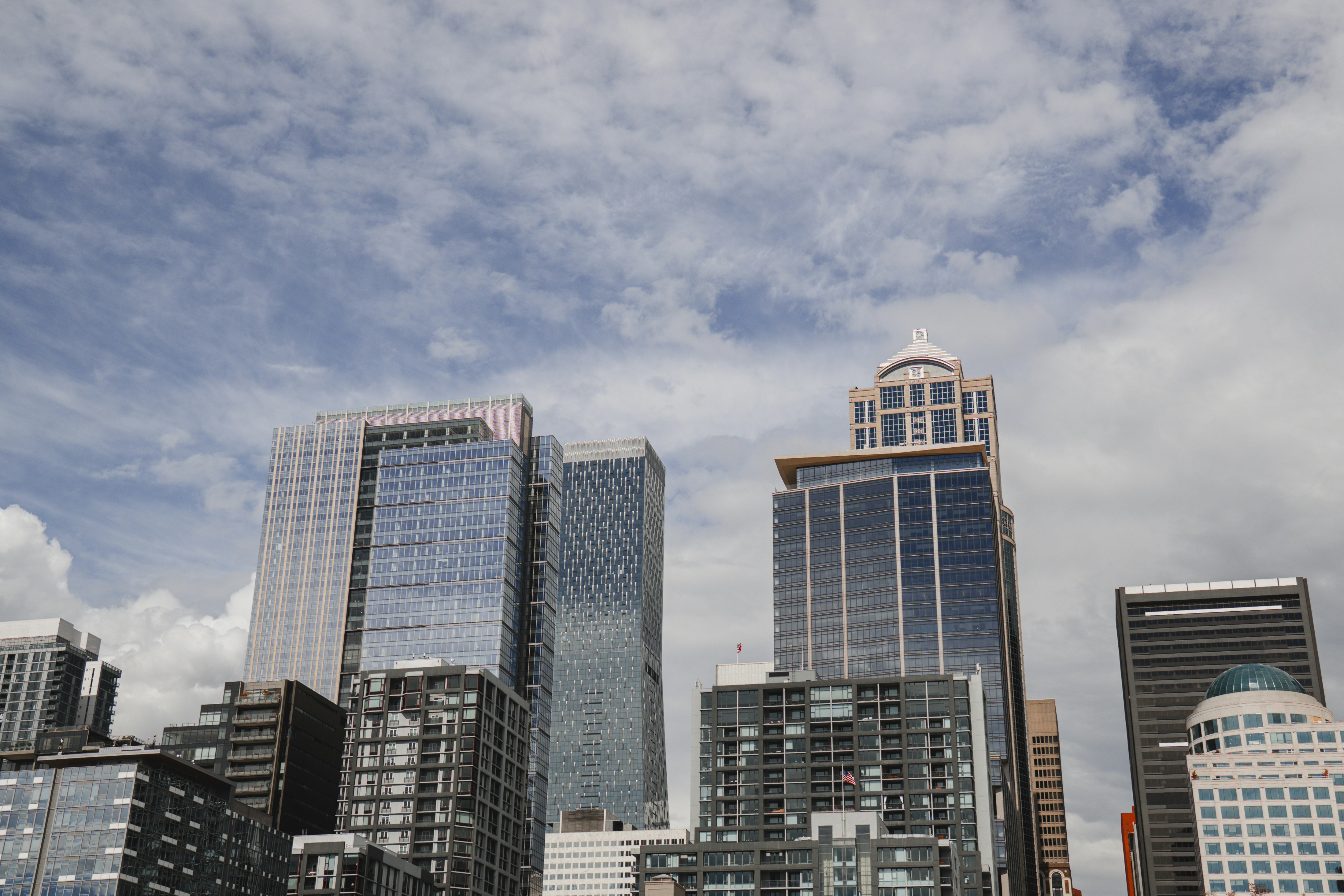 Modern glass skyscrapers rising against a cloudy blue sky in a city center