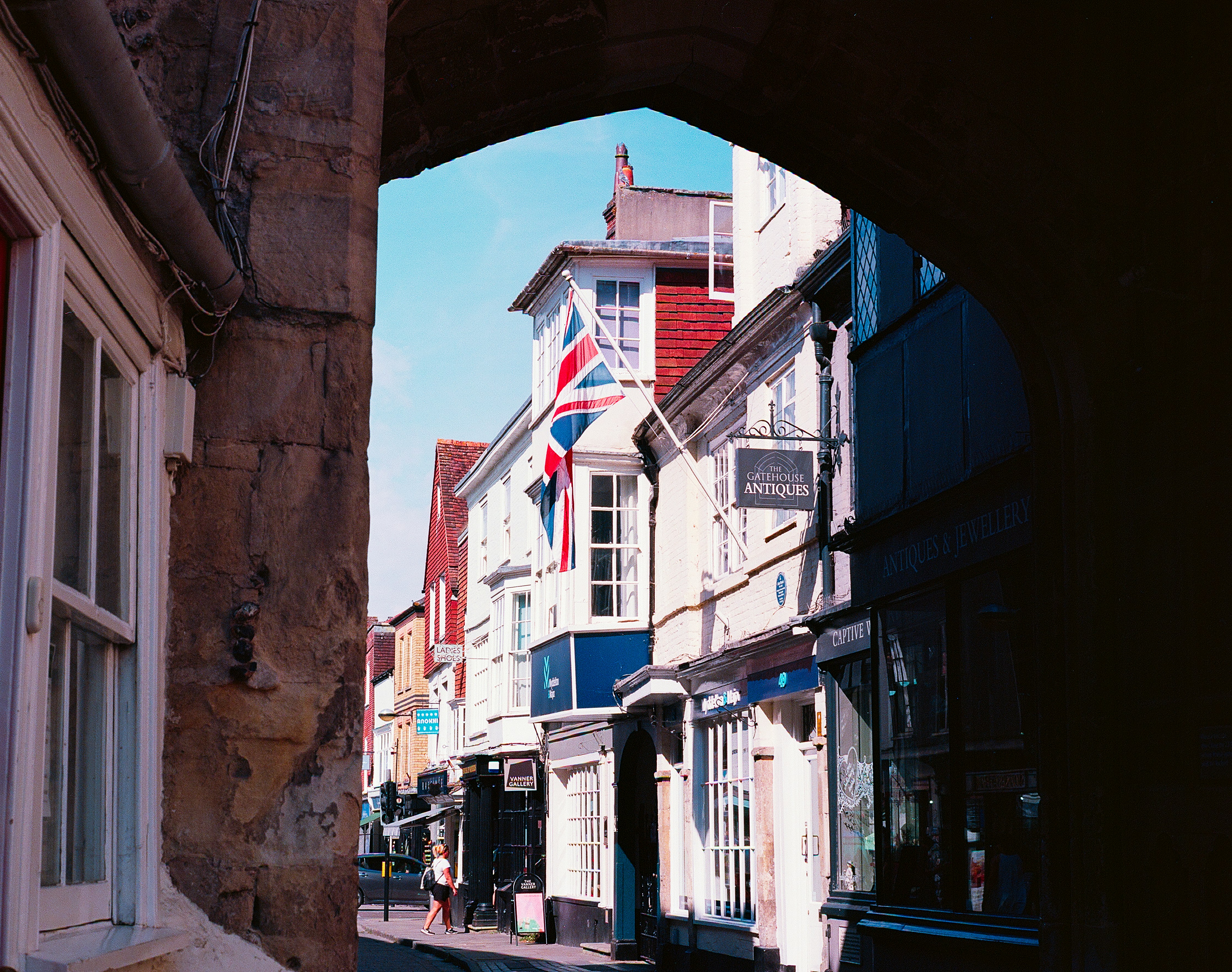 A British flag hanging from a building on a street with antique shops