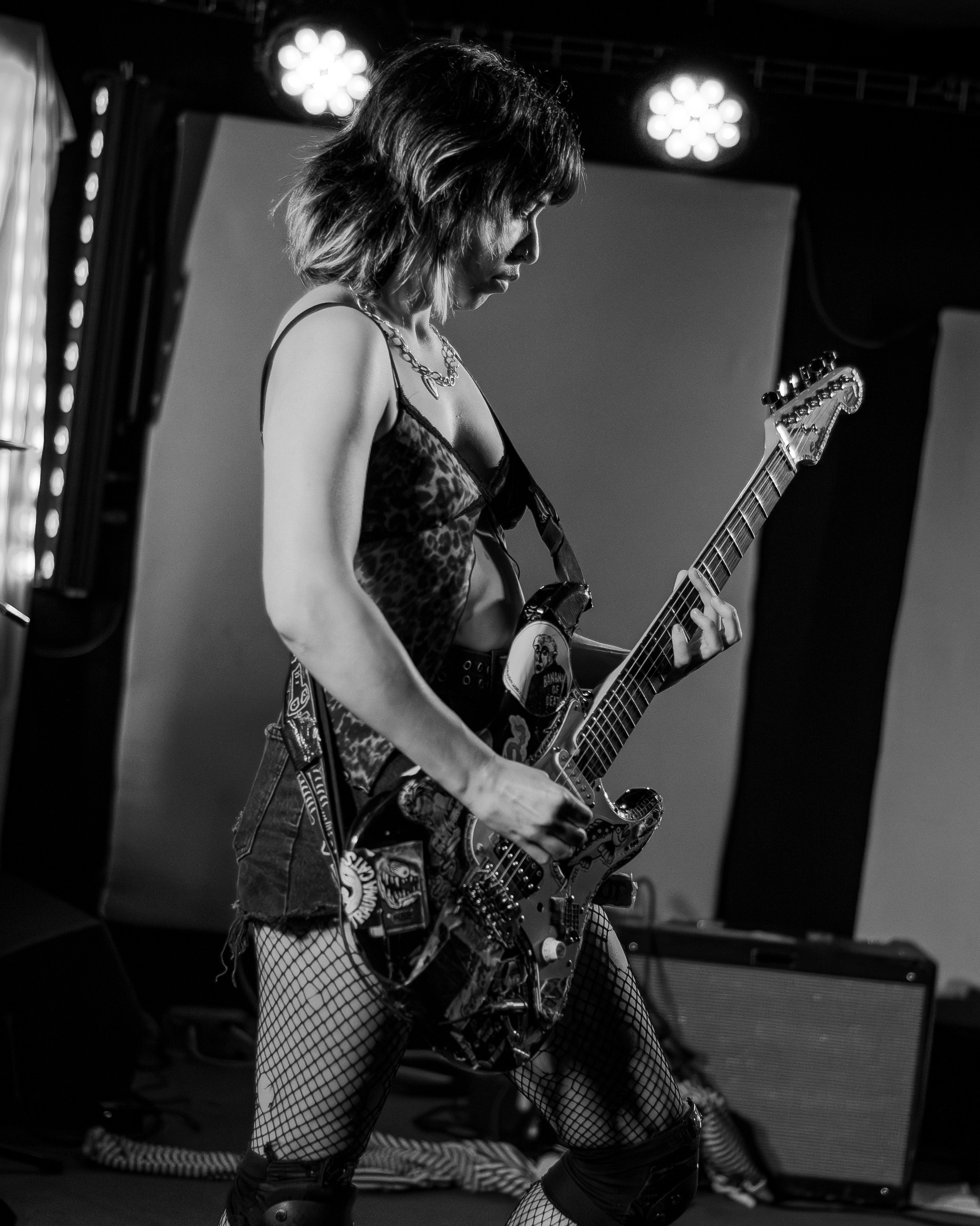 Una persona con una blusa de estampado de leopardo tocando una guitarra eléctrica en el escenario