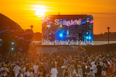A crowd at an outdoor music festival with a large screen reading Seaside