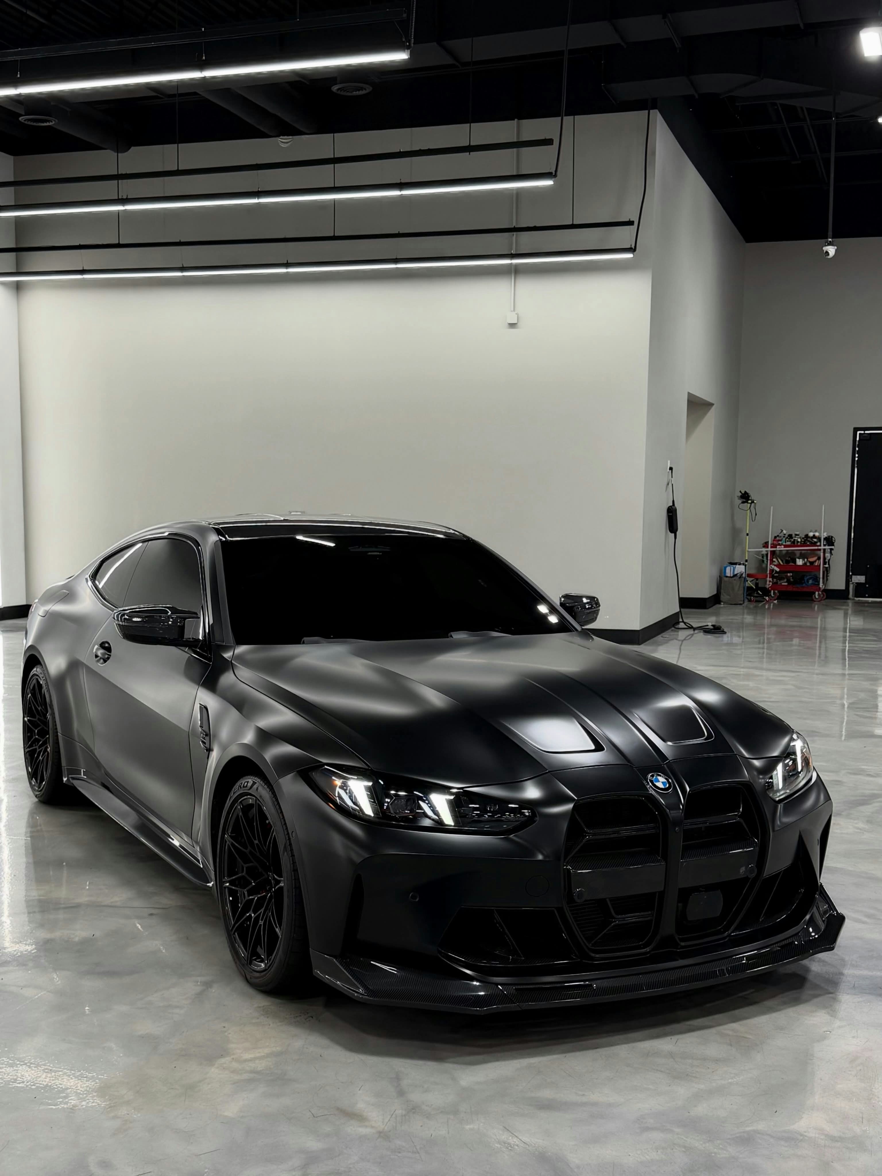 A matte black sports car parked on a polished concrete floor in a garage
