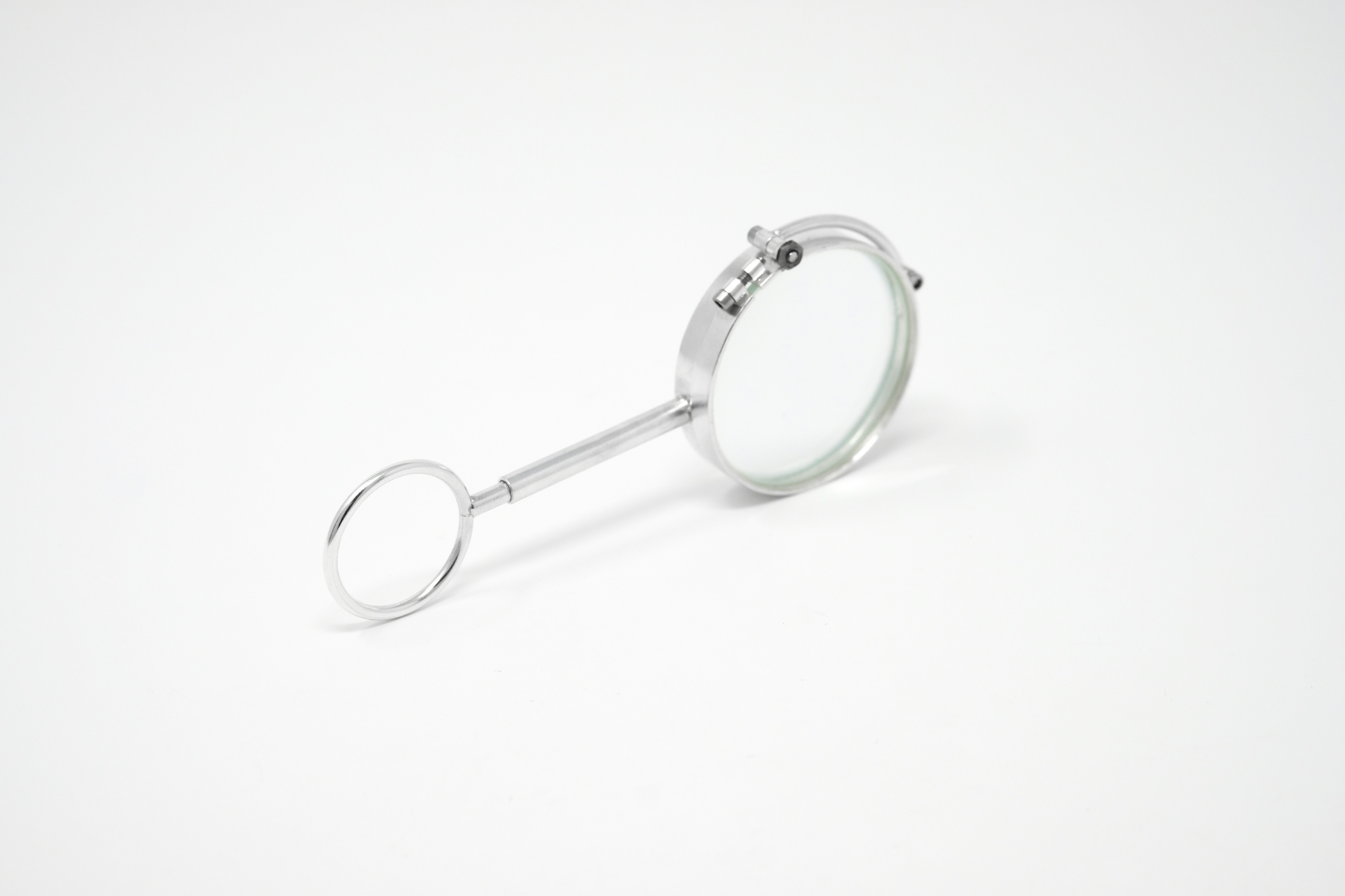 A silver magnifying glass with a circular handle on a plain white background