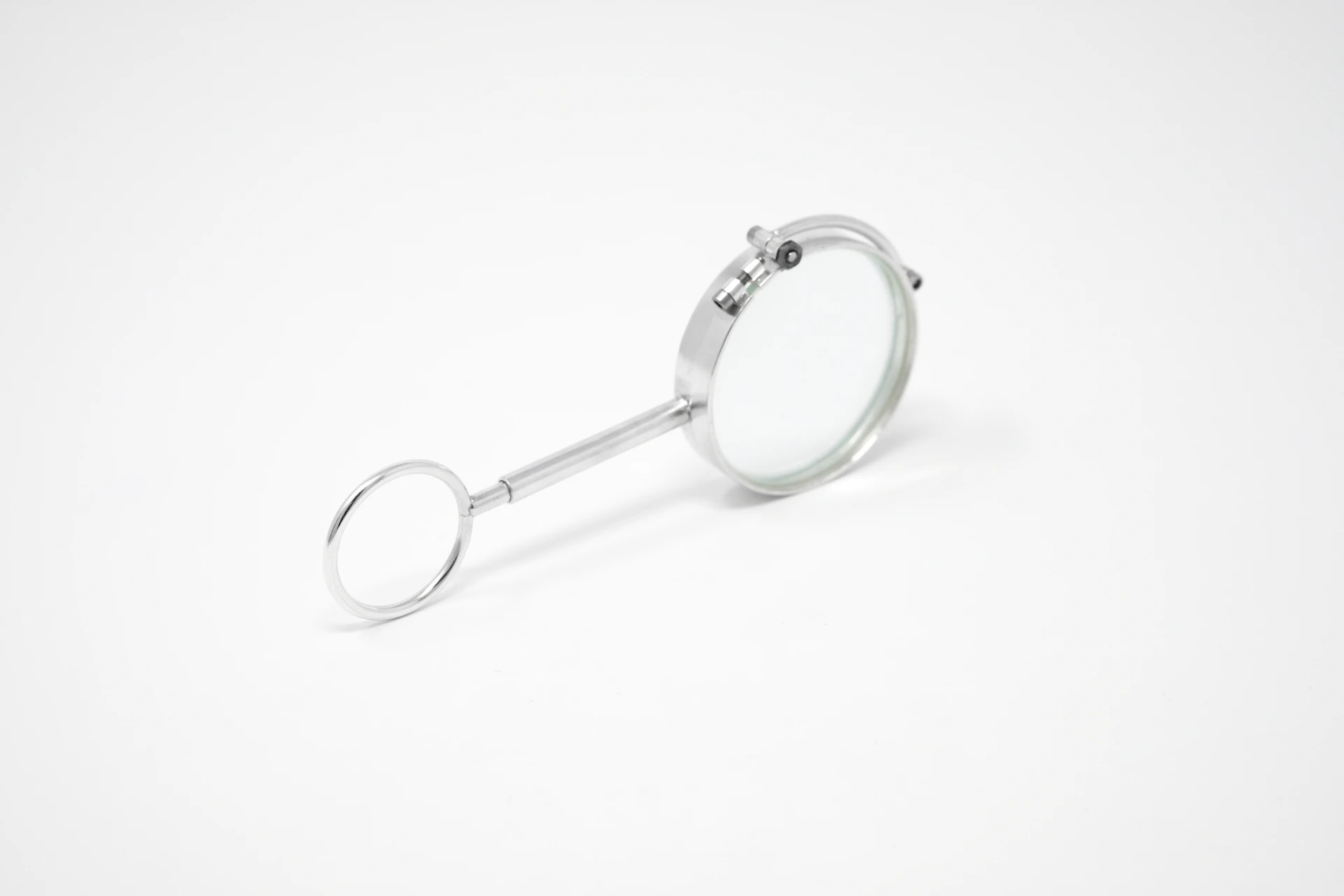 A silver magnifying glass with a circular handle on a plain white background