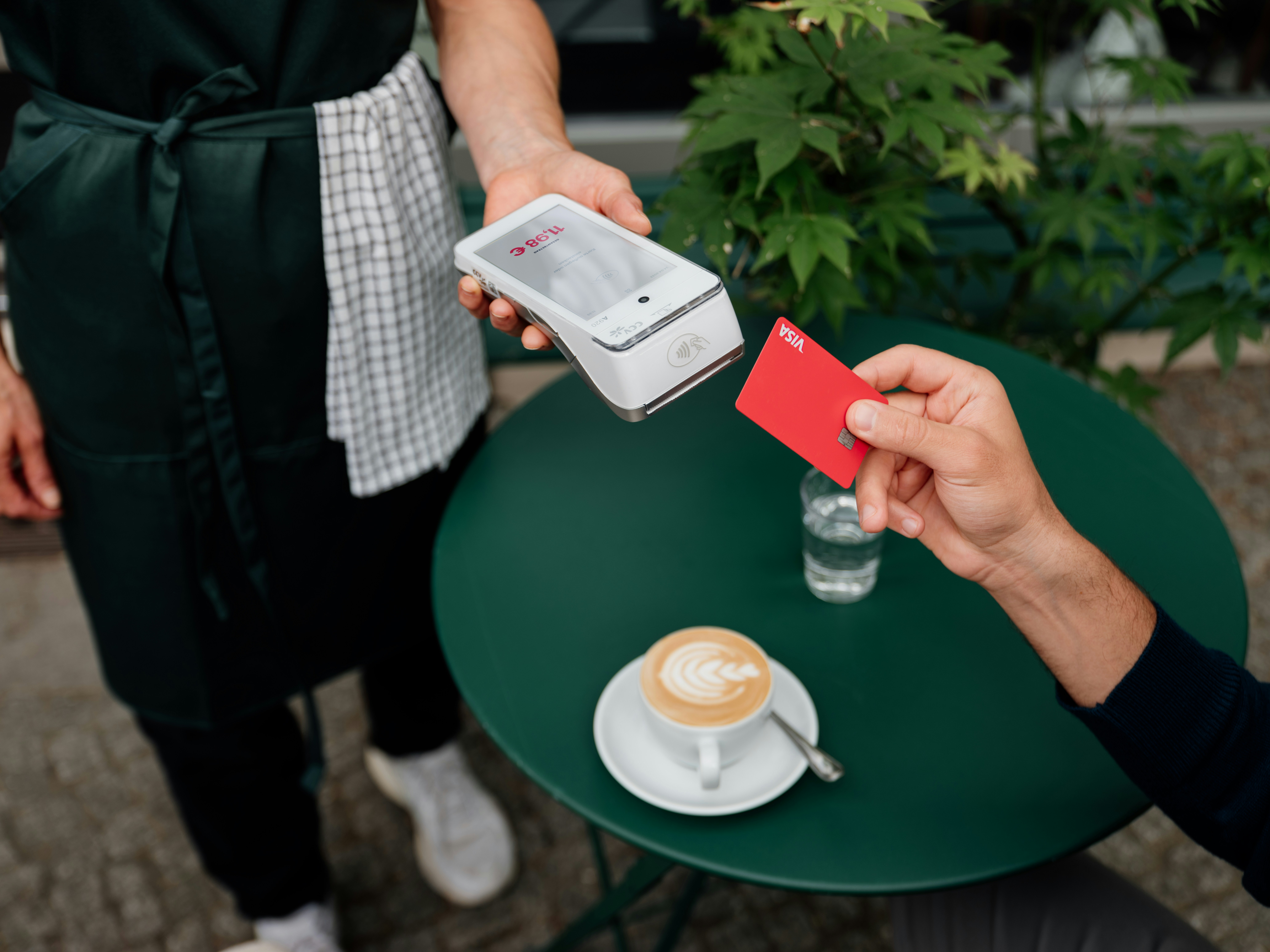 A person paying with a red credit card at a cafe table