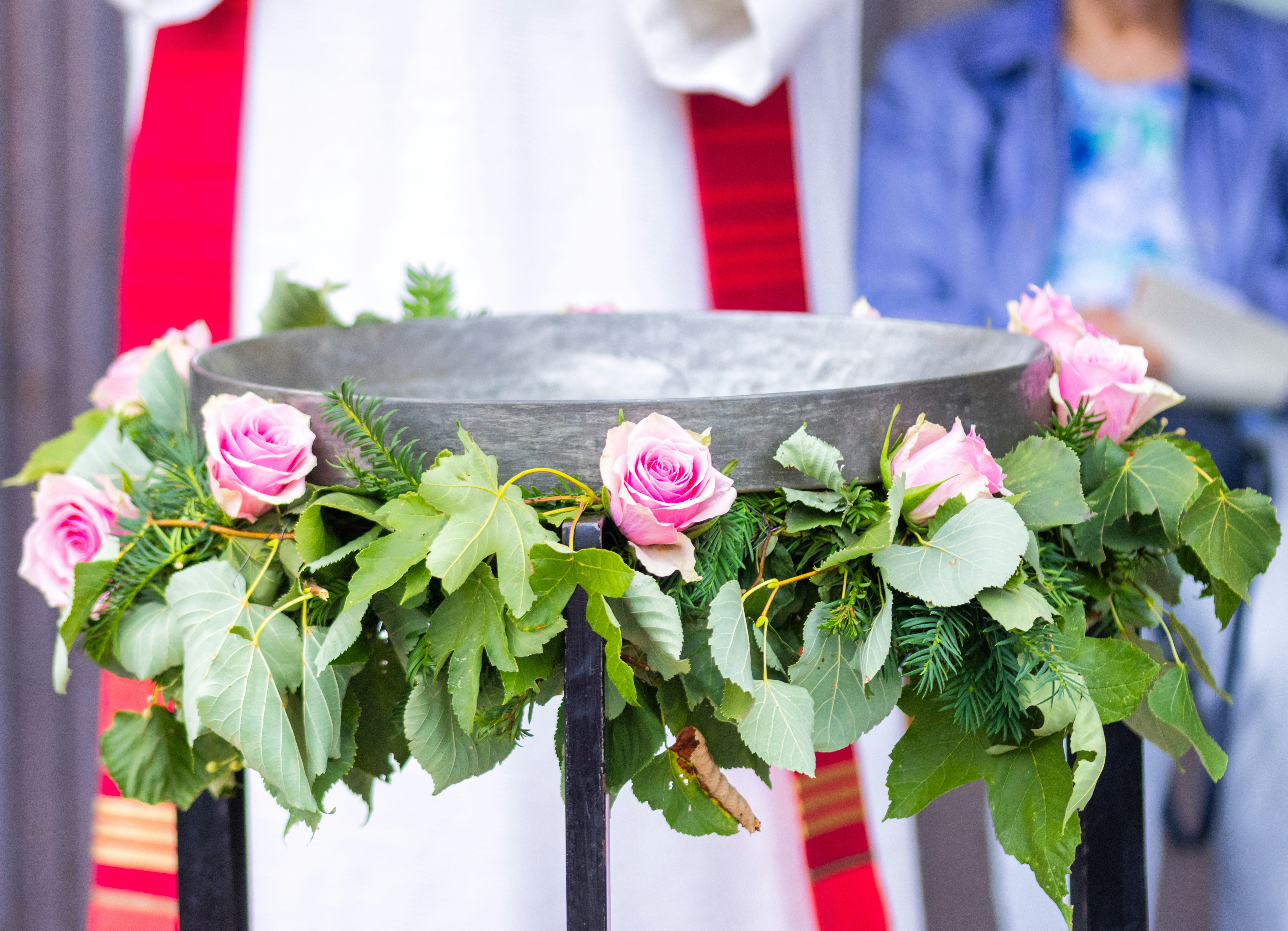 A stone baptismal font decorated with pink roses and green leaves